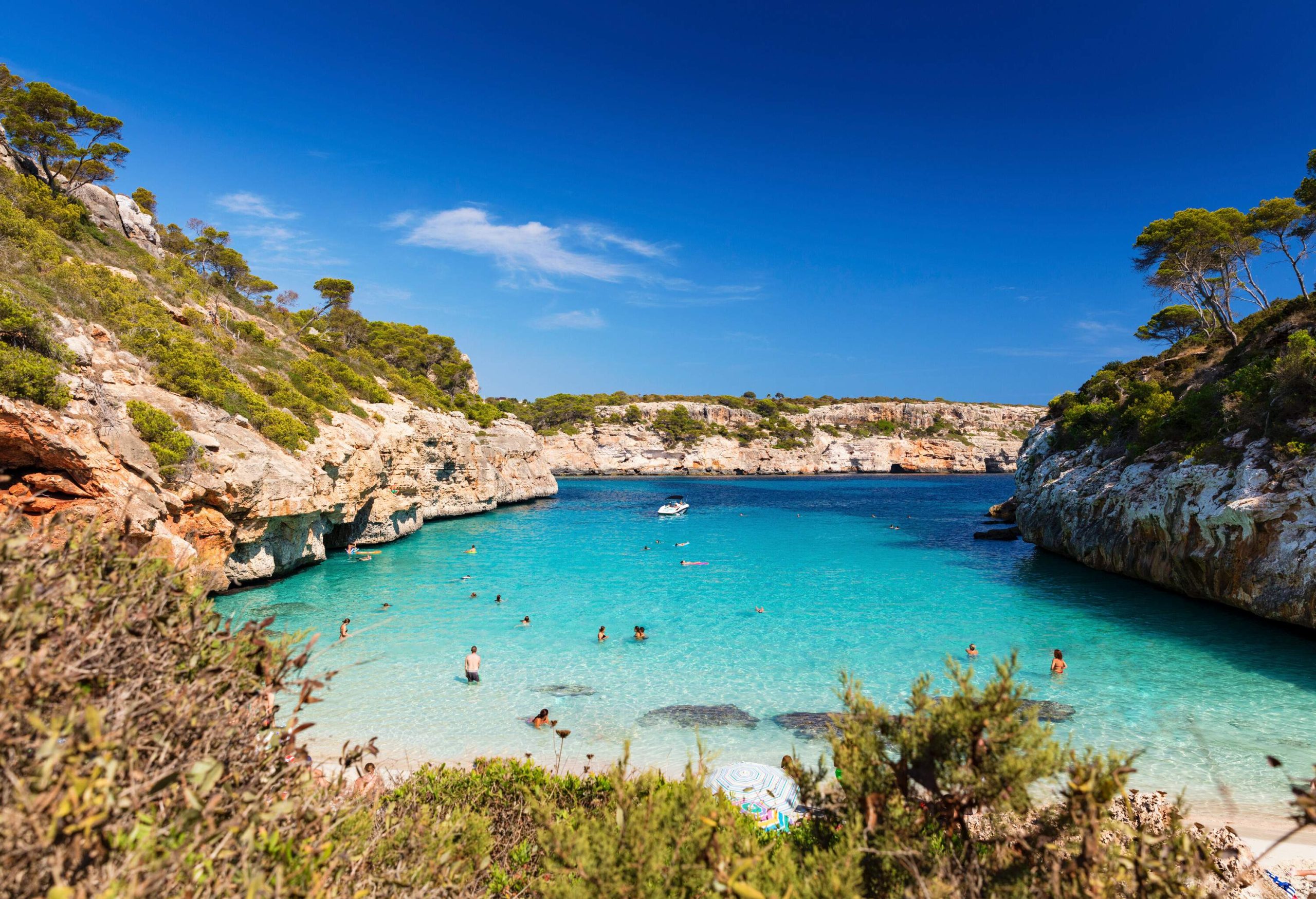 People enjoy the calm crystal clear turquoise waters along the rocky cliffs.