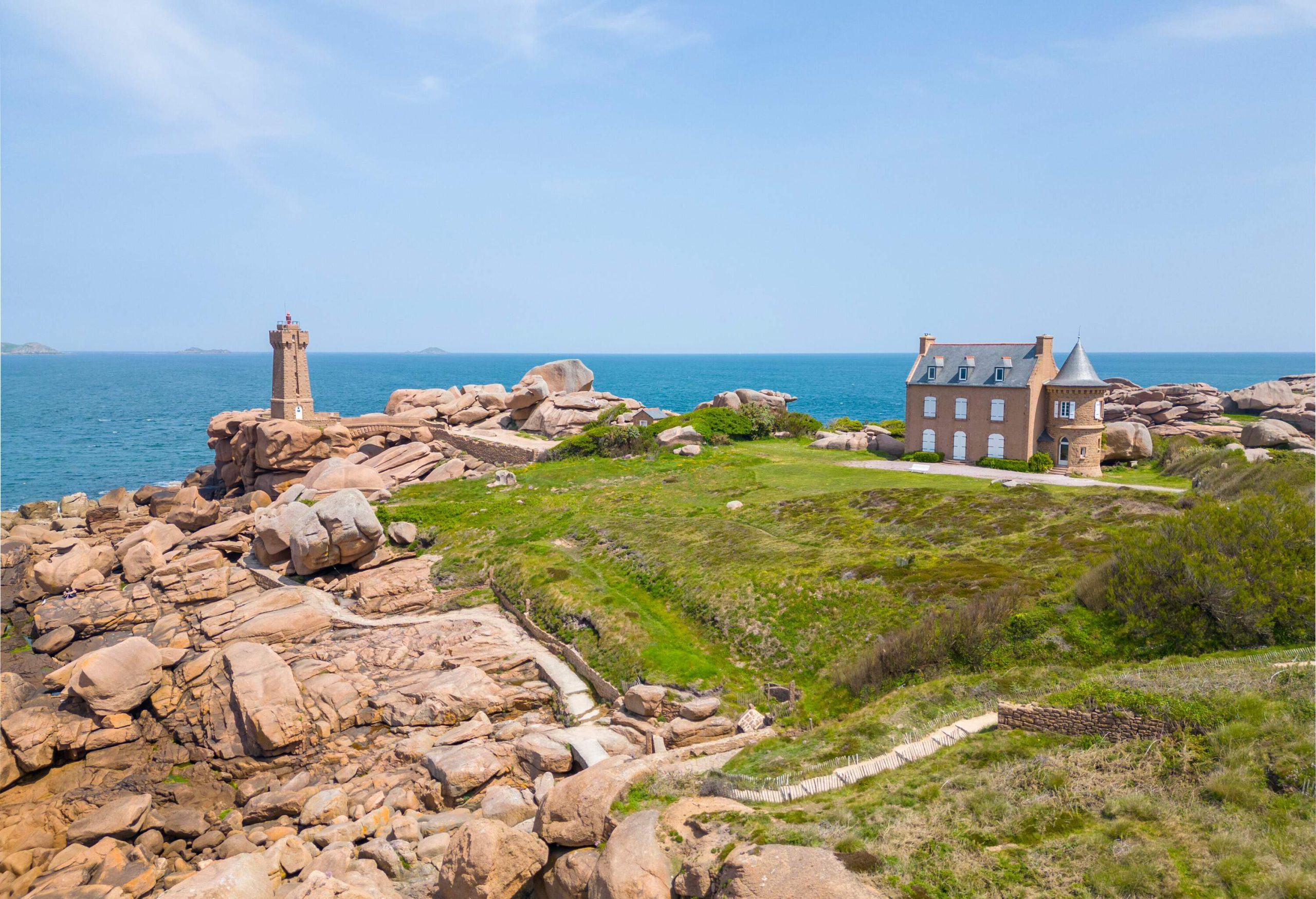 View of ruggedcoastal landscape with pink granite, a lighthouse and castle by the sea