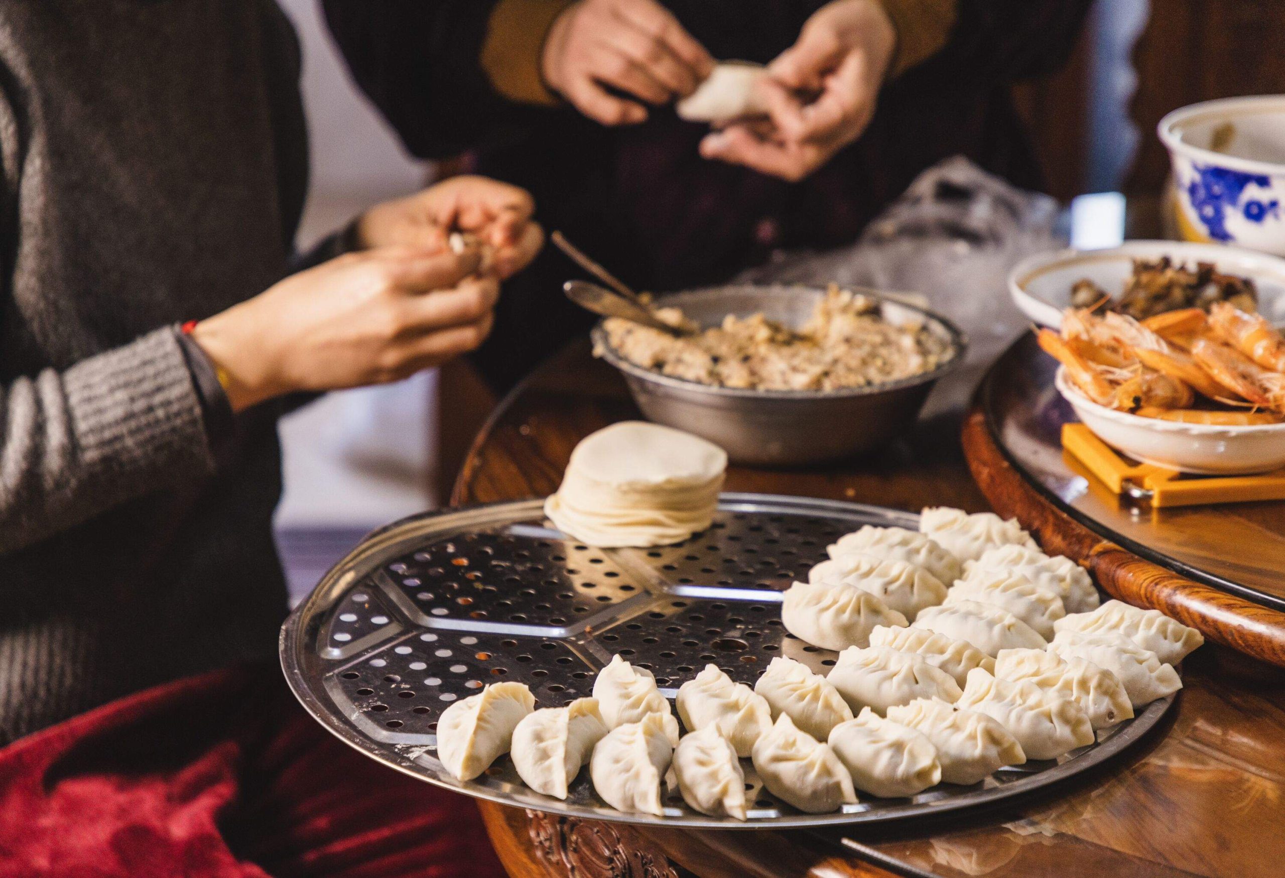 asian mother and adult daughter making dumpling together