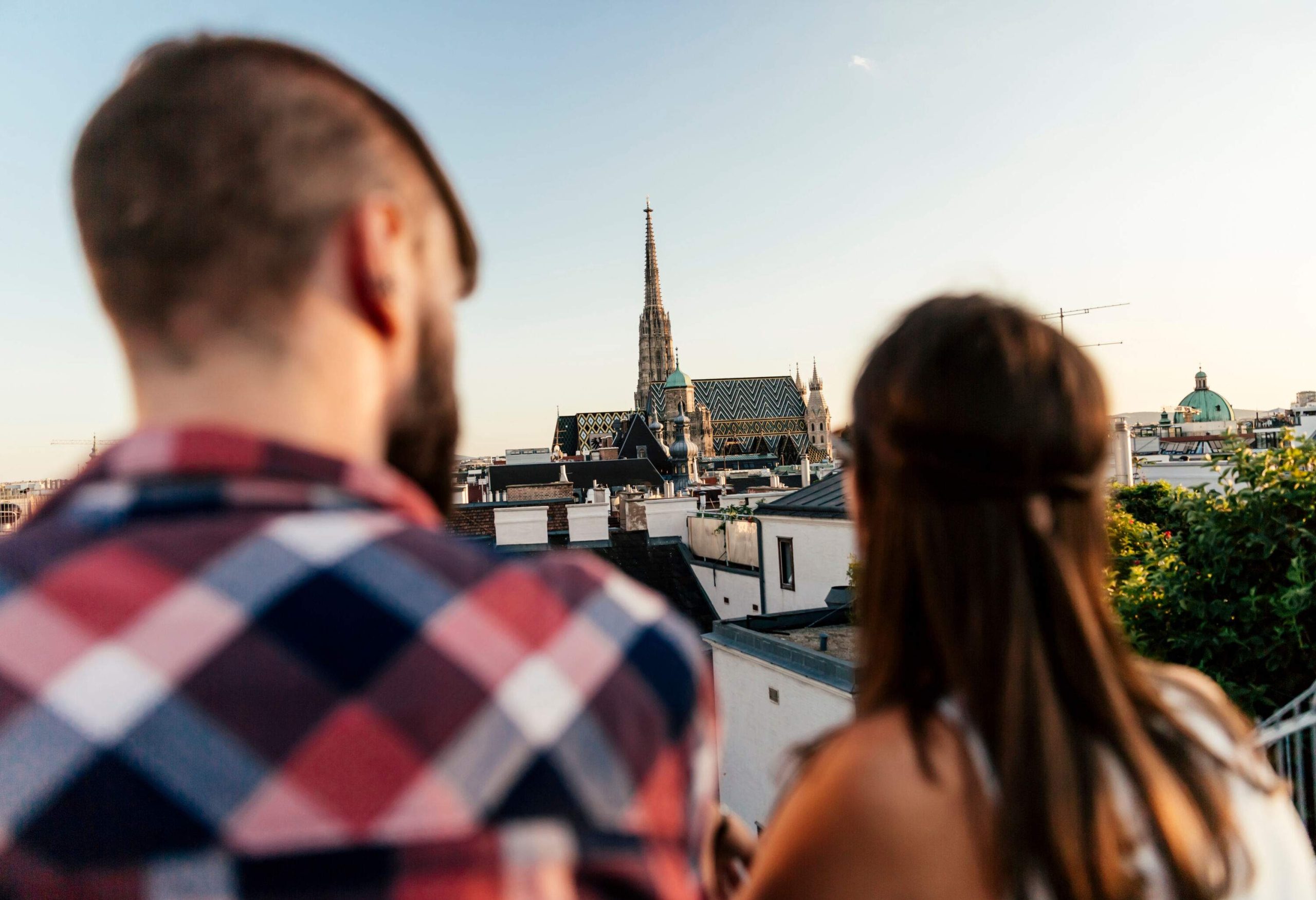 A man and woman on a terrace, looking over the city at a church spire.