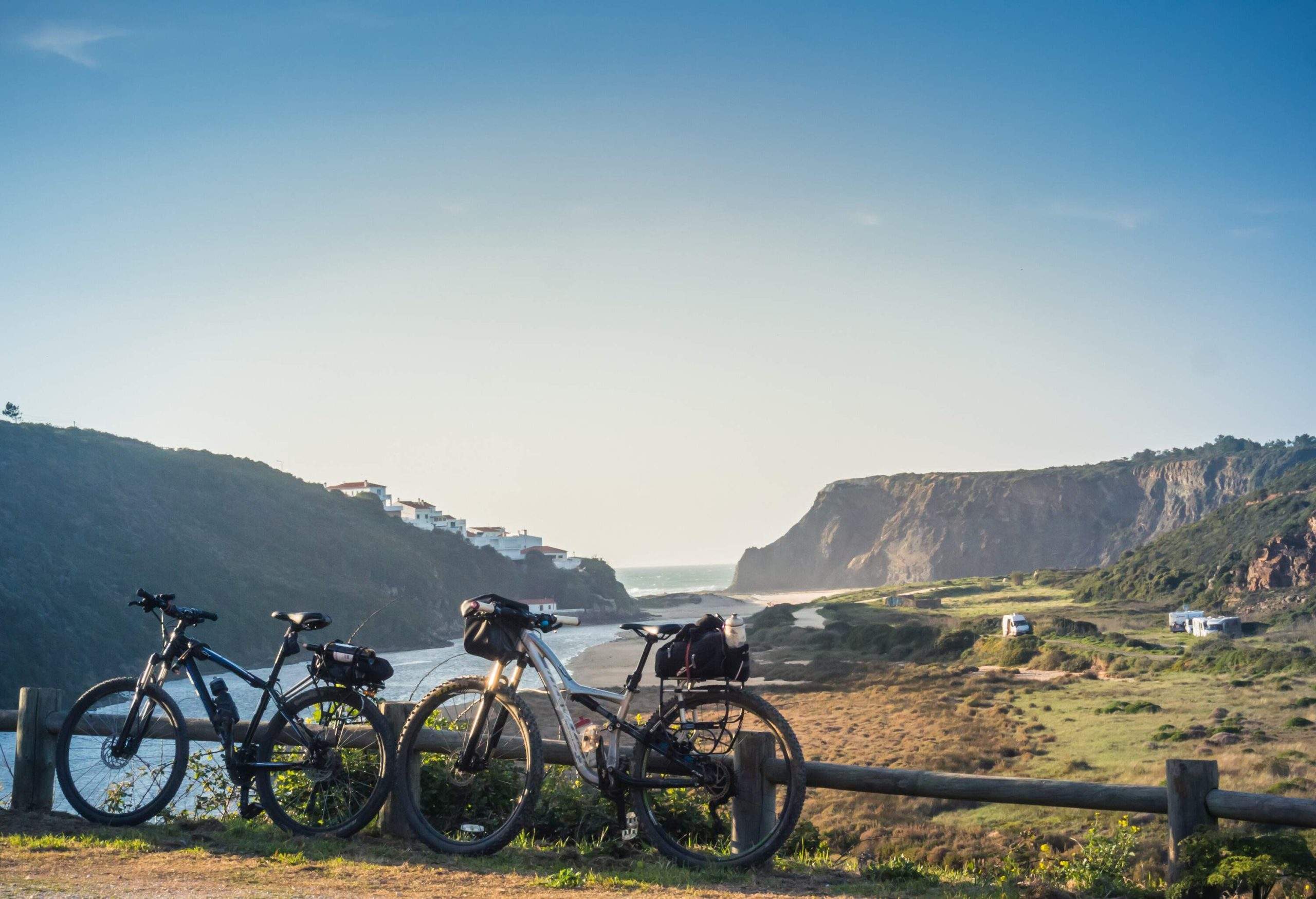 Two bicycles parked on a wooden fence with overlooking views of a stream across sloping hills.