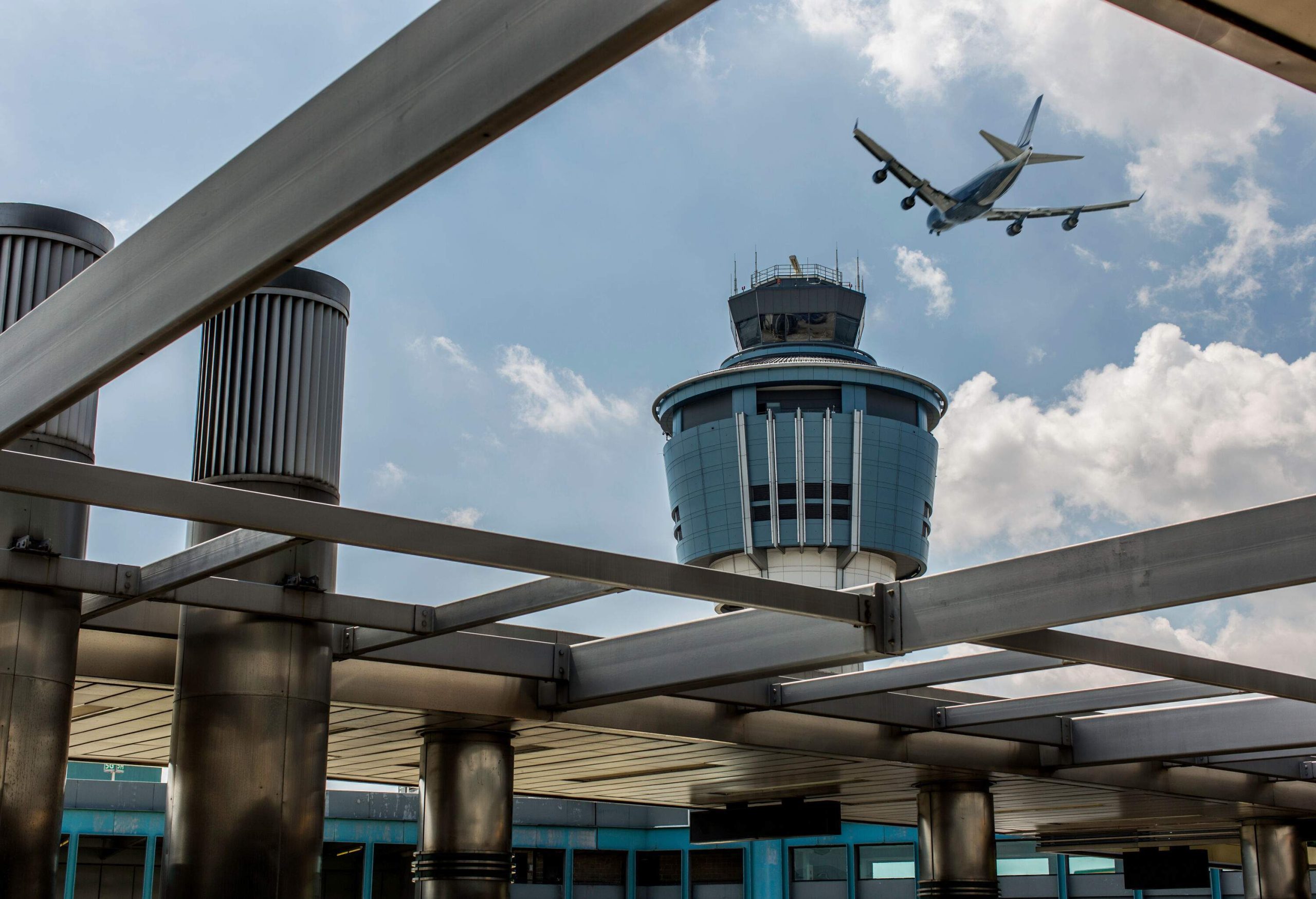 An airplane flying over the air traffic control tower at the airport.
