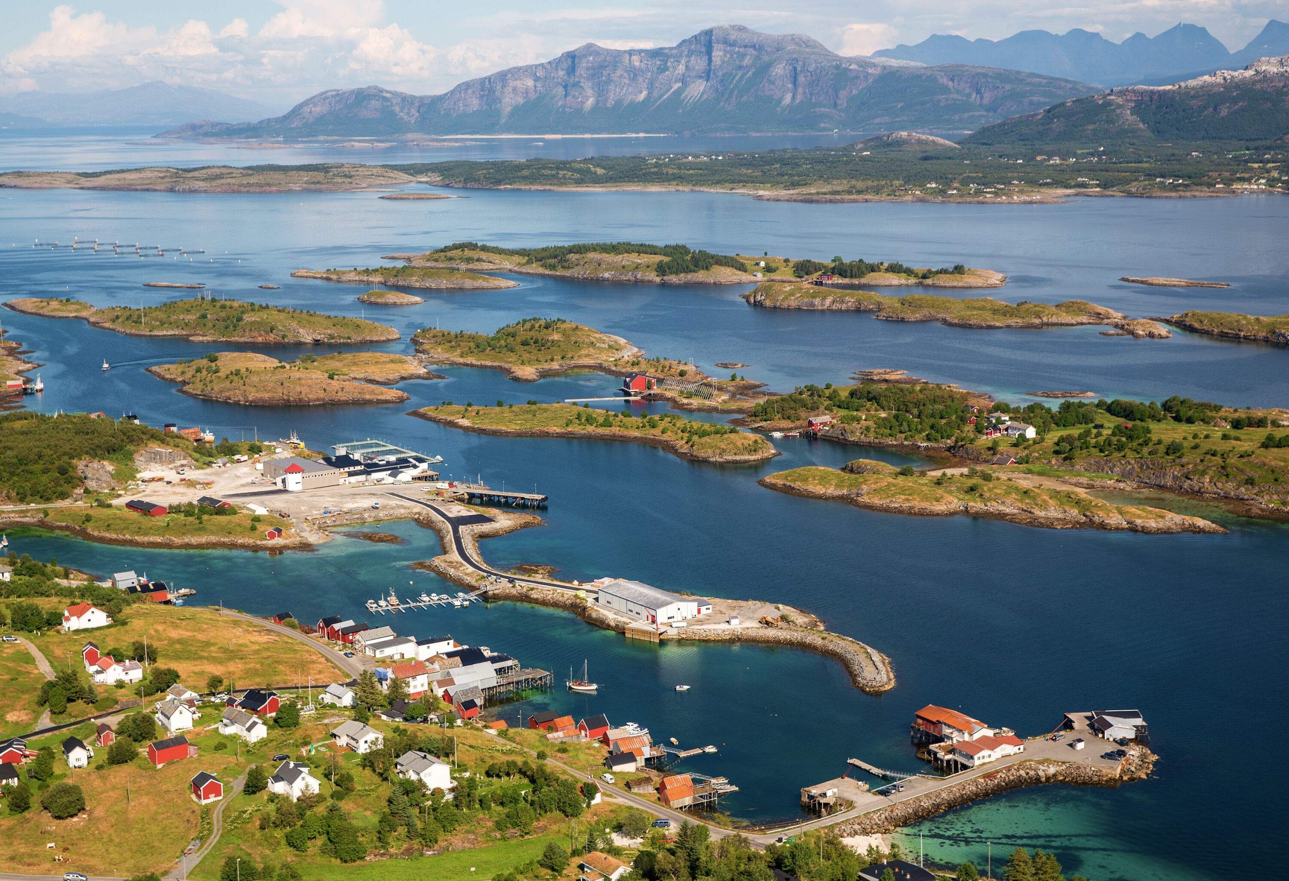 A rural village with a sheltered harbour next to small islands in a lake.