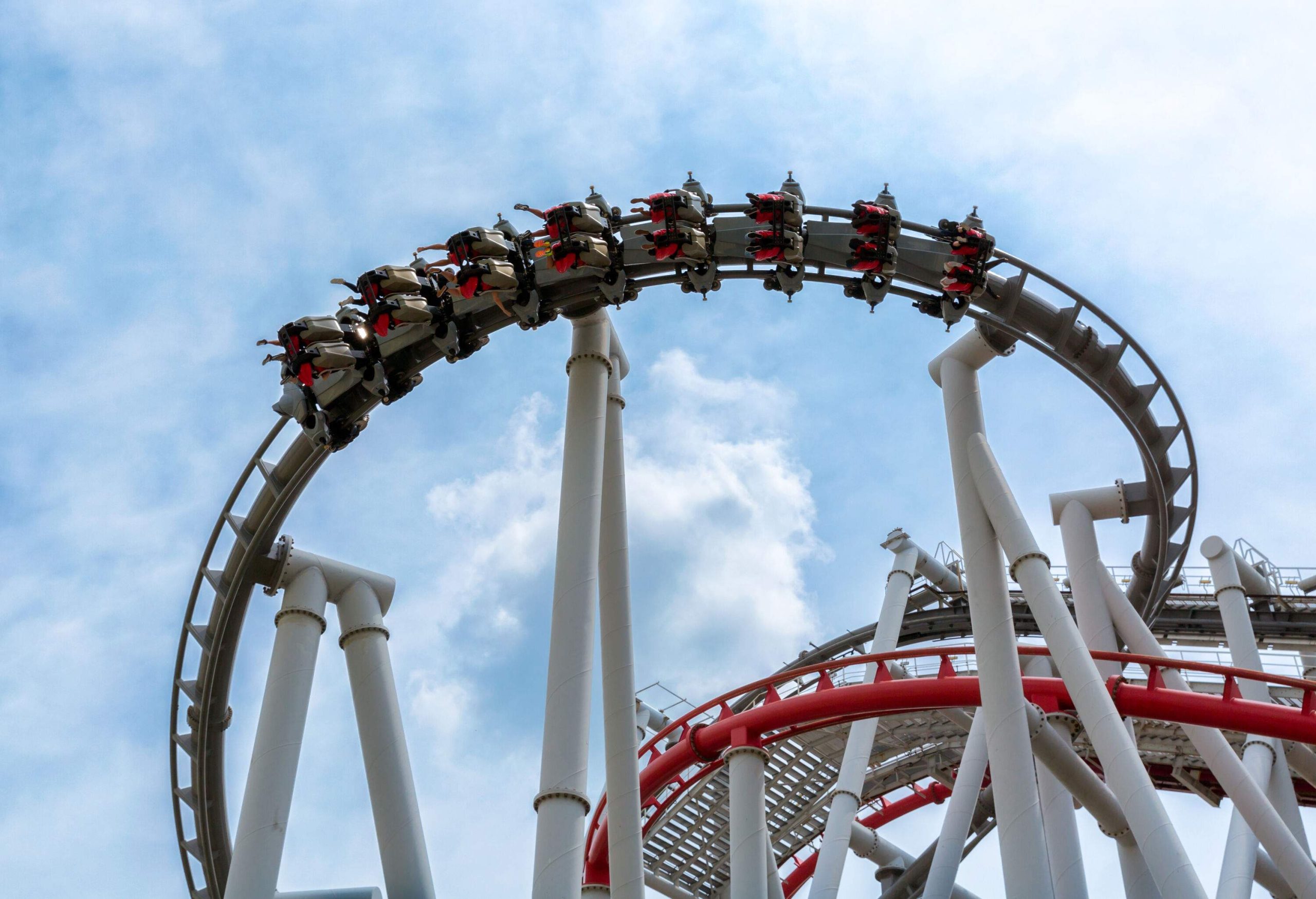 People on the winding roller coaster ride against the clear blue sky.