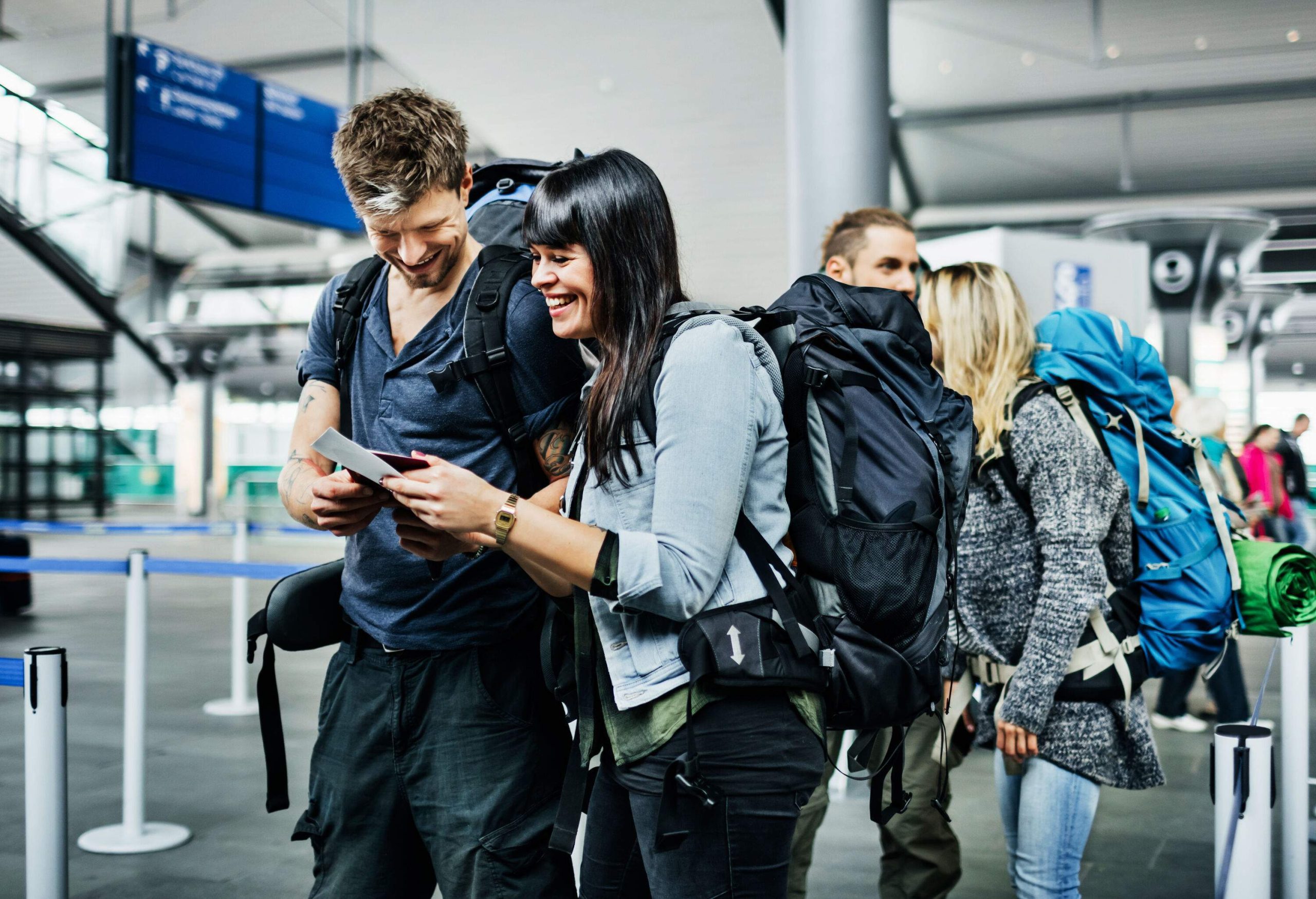 Group of young backpackers waiting at an airline checkin counter for their boarding passes