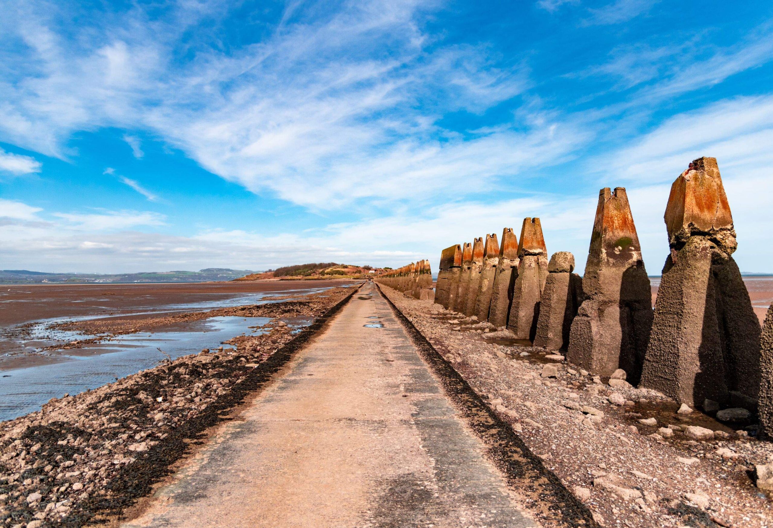 Causeway to Cramond Island in Edinburgh, Scotland, emerged at low tide. To the side, appears a WWII anti-tank barricade