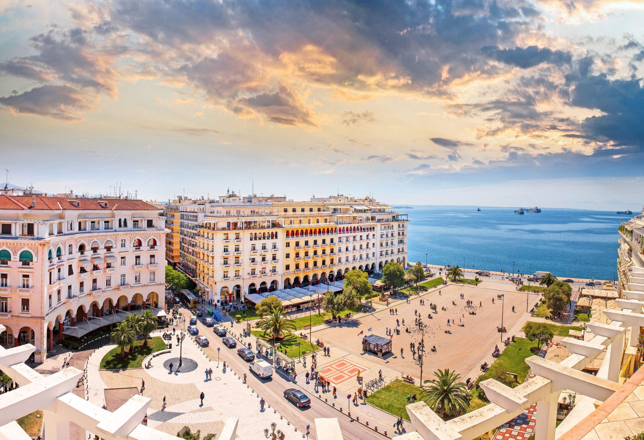 A waterfront city square surrounded by huge buildings with impressive façades.