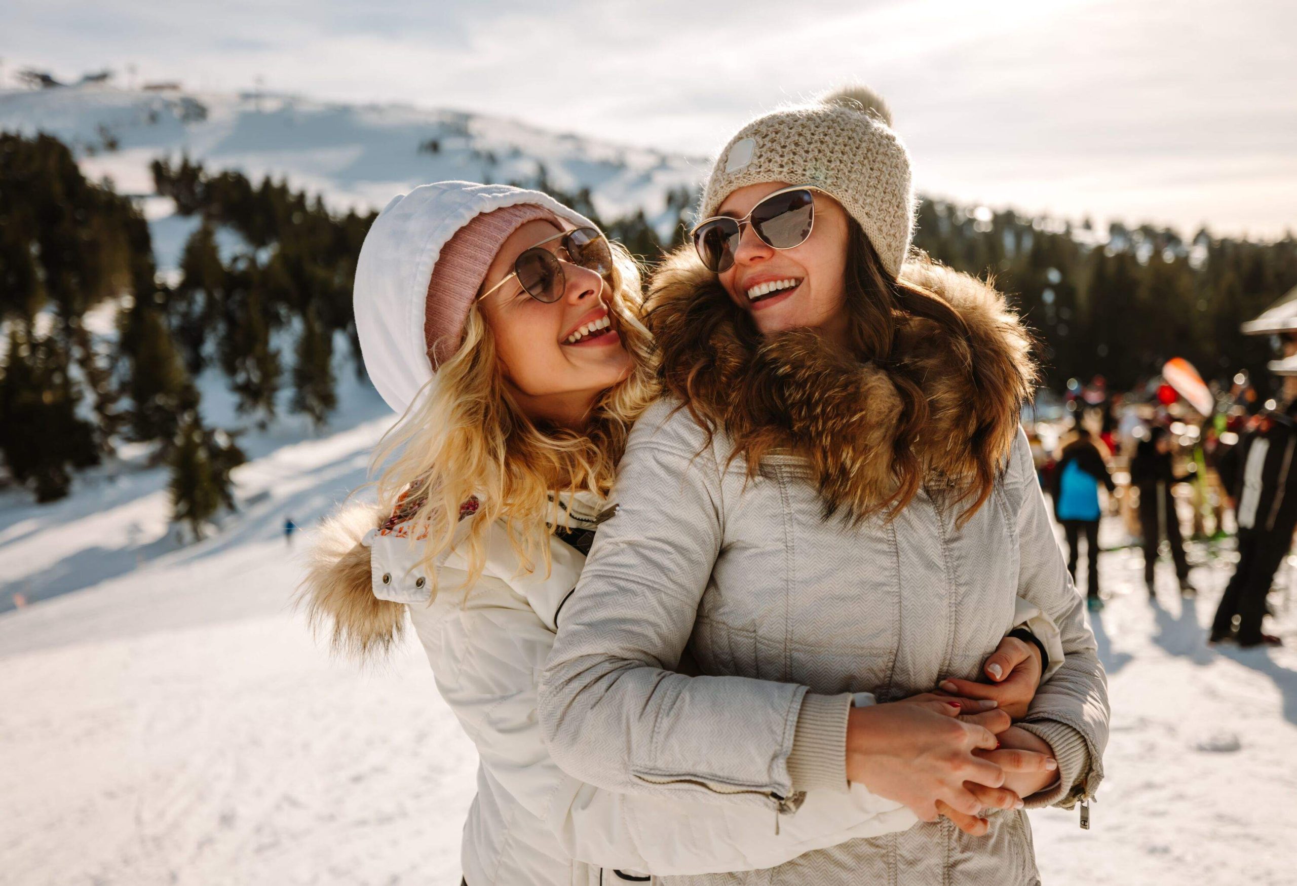 Portrait of happy female friends on winter vacation, standing and hugging on mountain