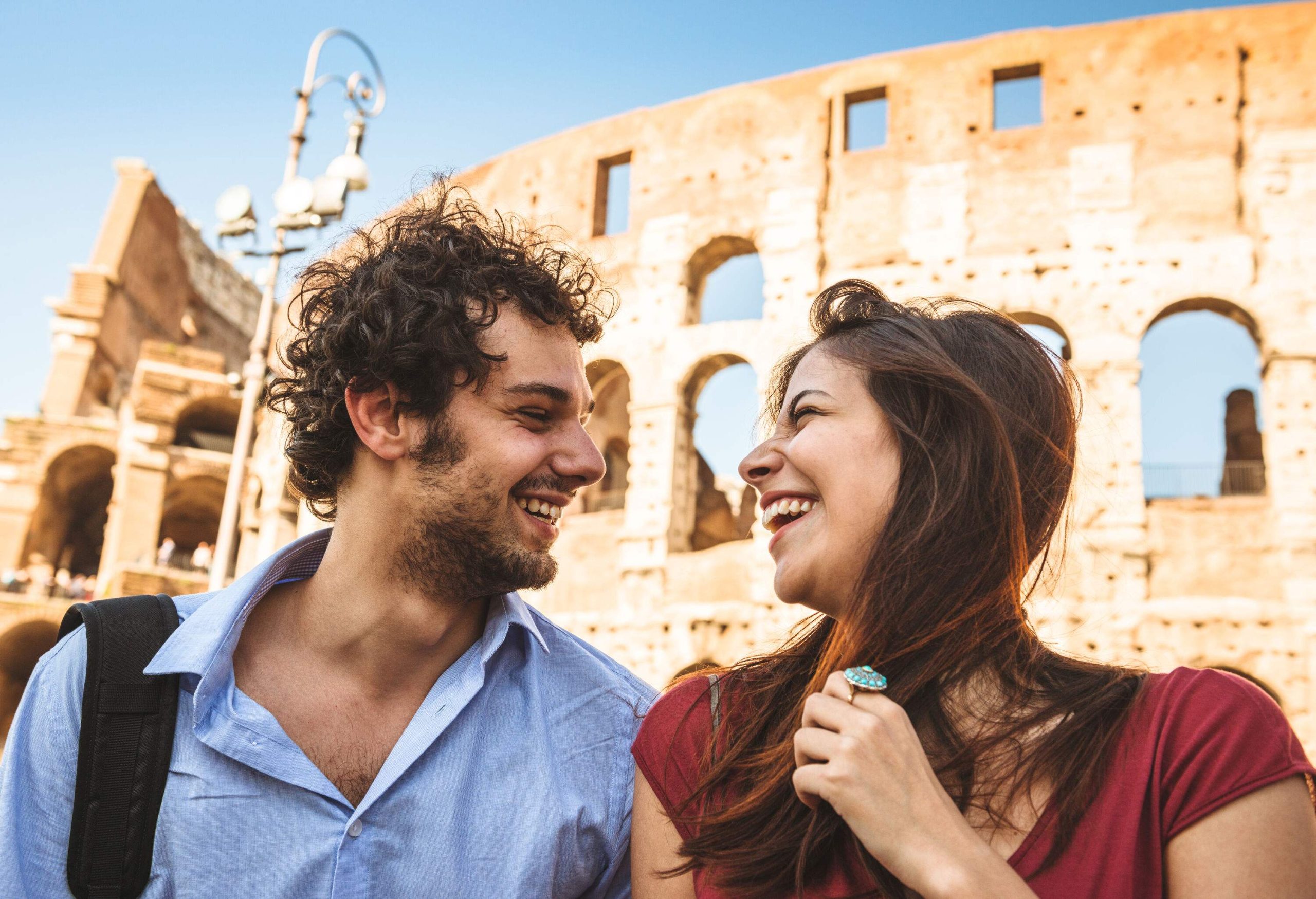 Couple looking at each other laughing in front of ancient roman ruin