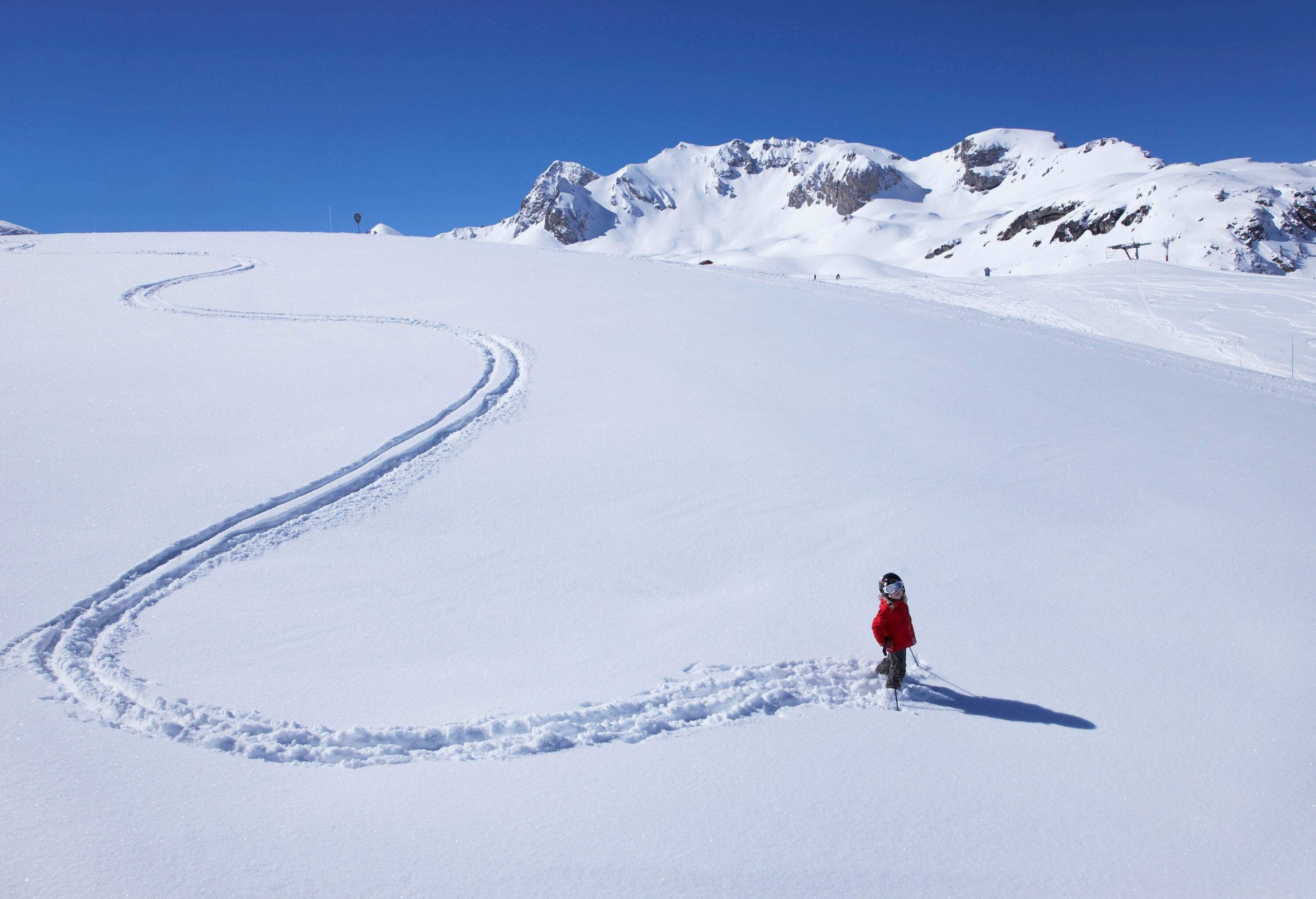 A skier glides over the snow creating a pattern of curved lines.