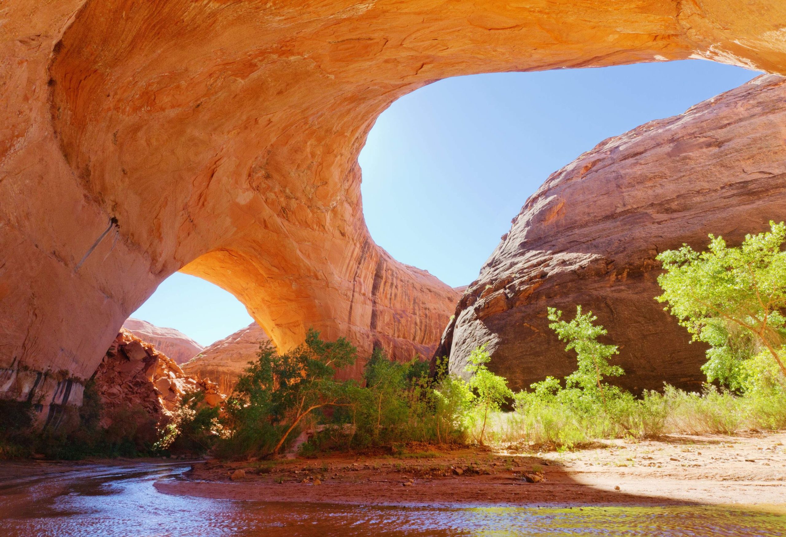 A stream flowing beneath a spectacular geological formation. 