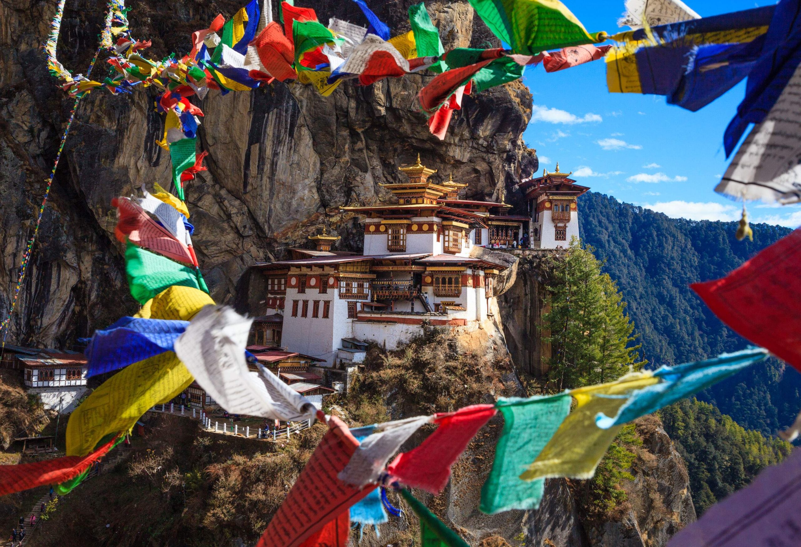 Paro Taktsang is a cliffside Buddhist monastery with colourful hanged banners in the foreground.