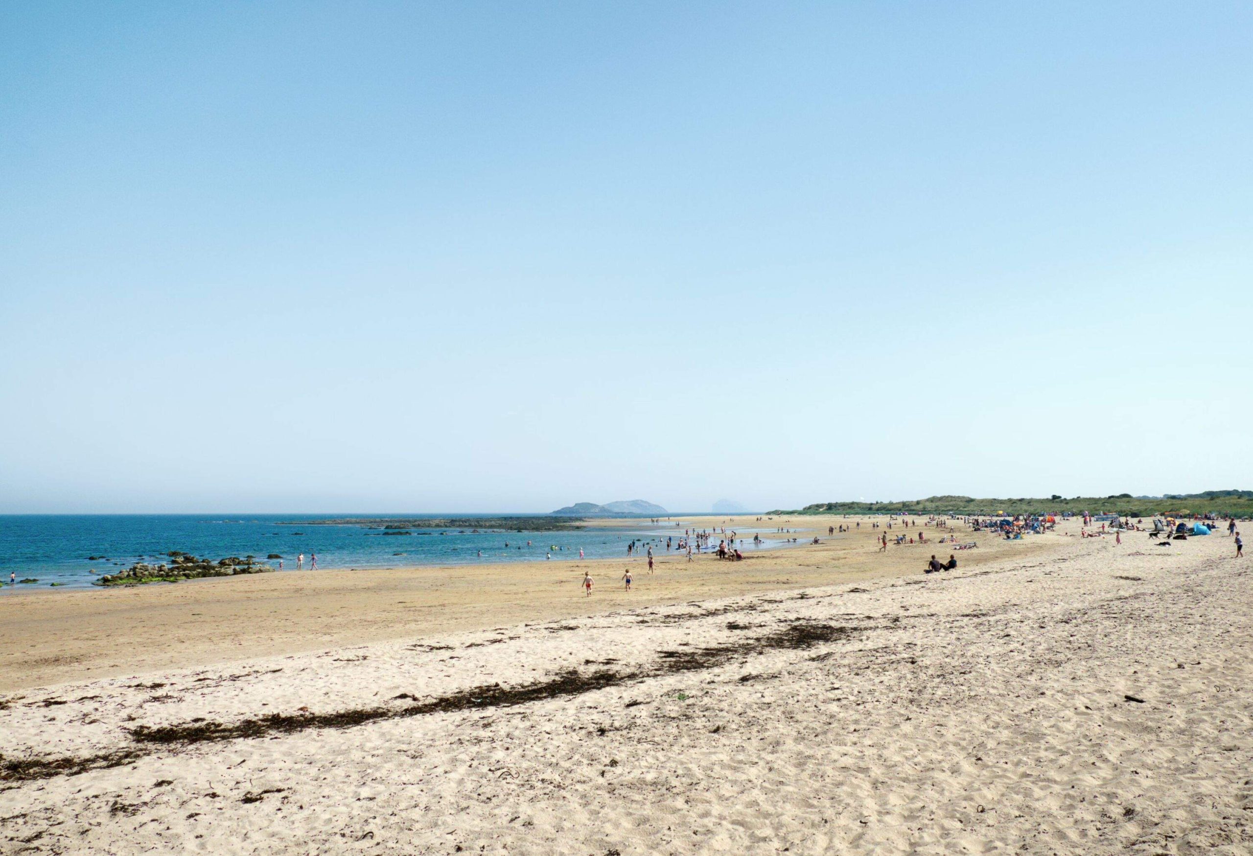 People relax on the beach with a blue sky