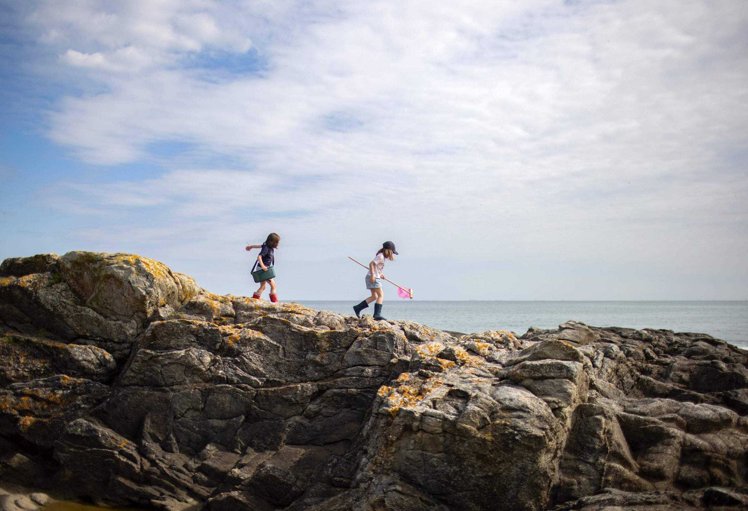 Two children exploring rocks by the sea