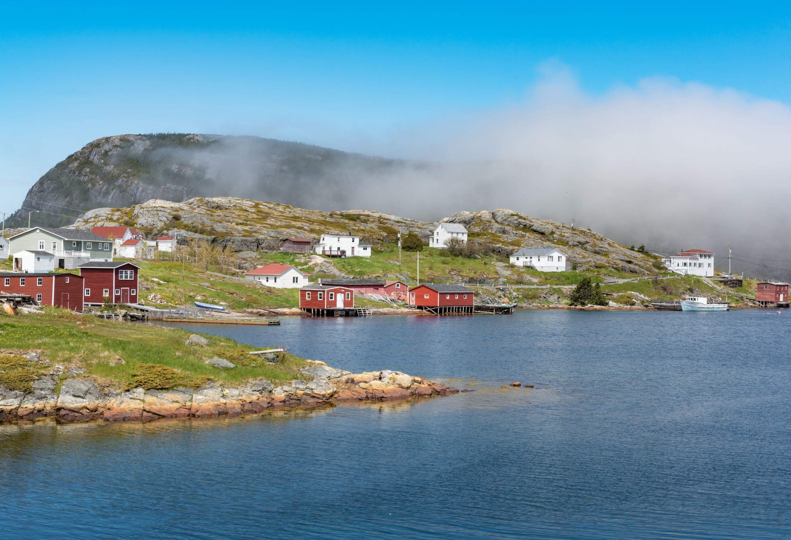 A residential neighbourhood with homes perched on rock hills along a calm harbour.