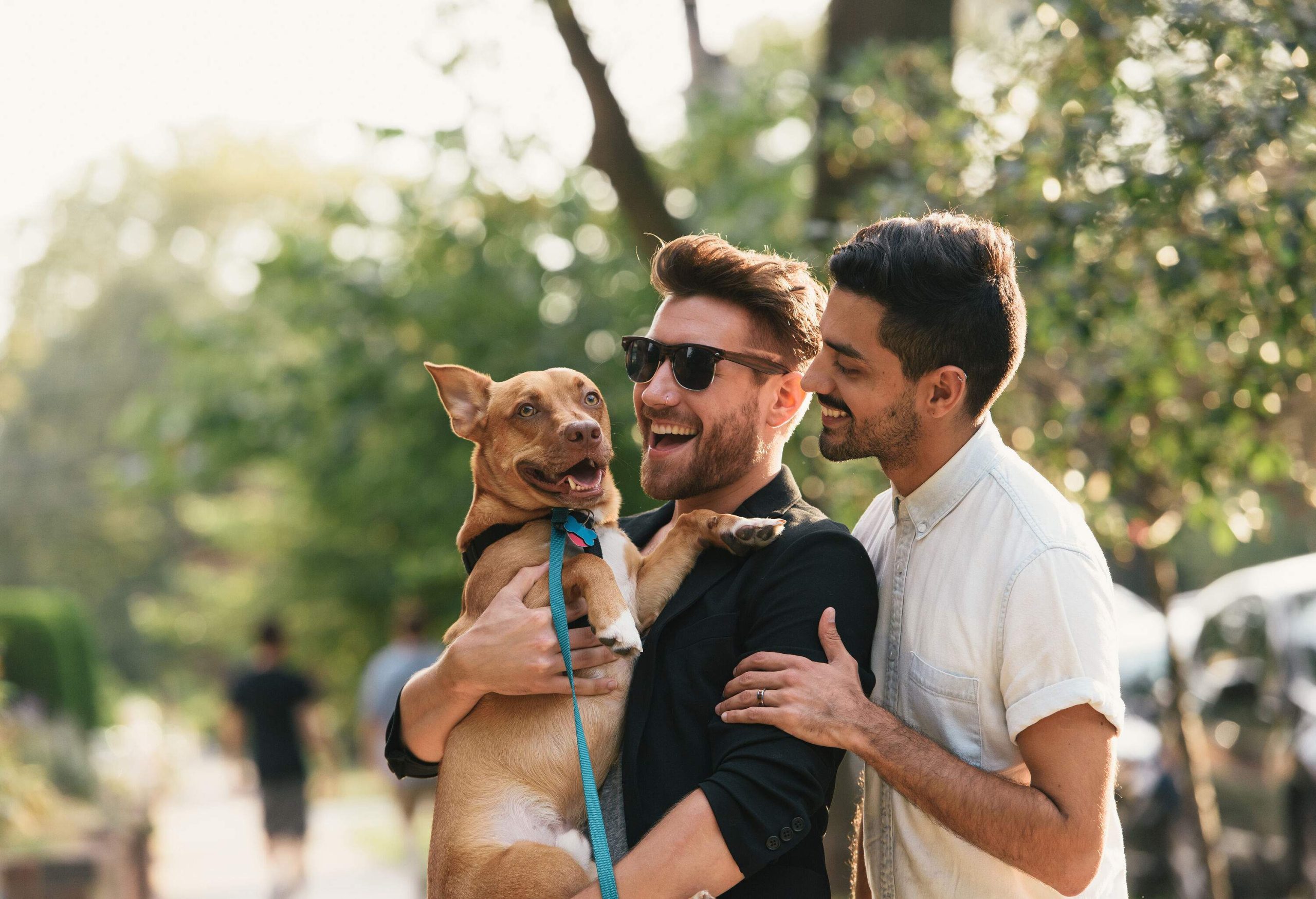 Happy male couple with one of the men carrying a dog.