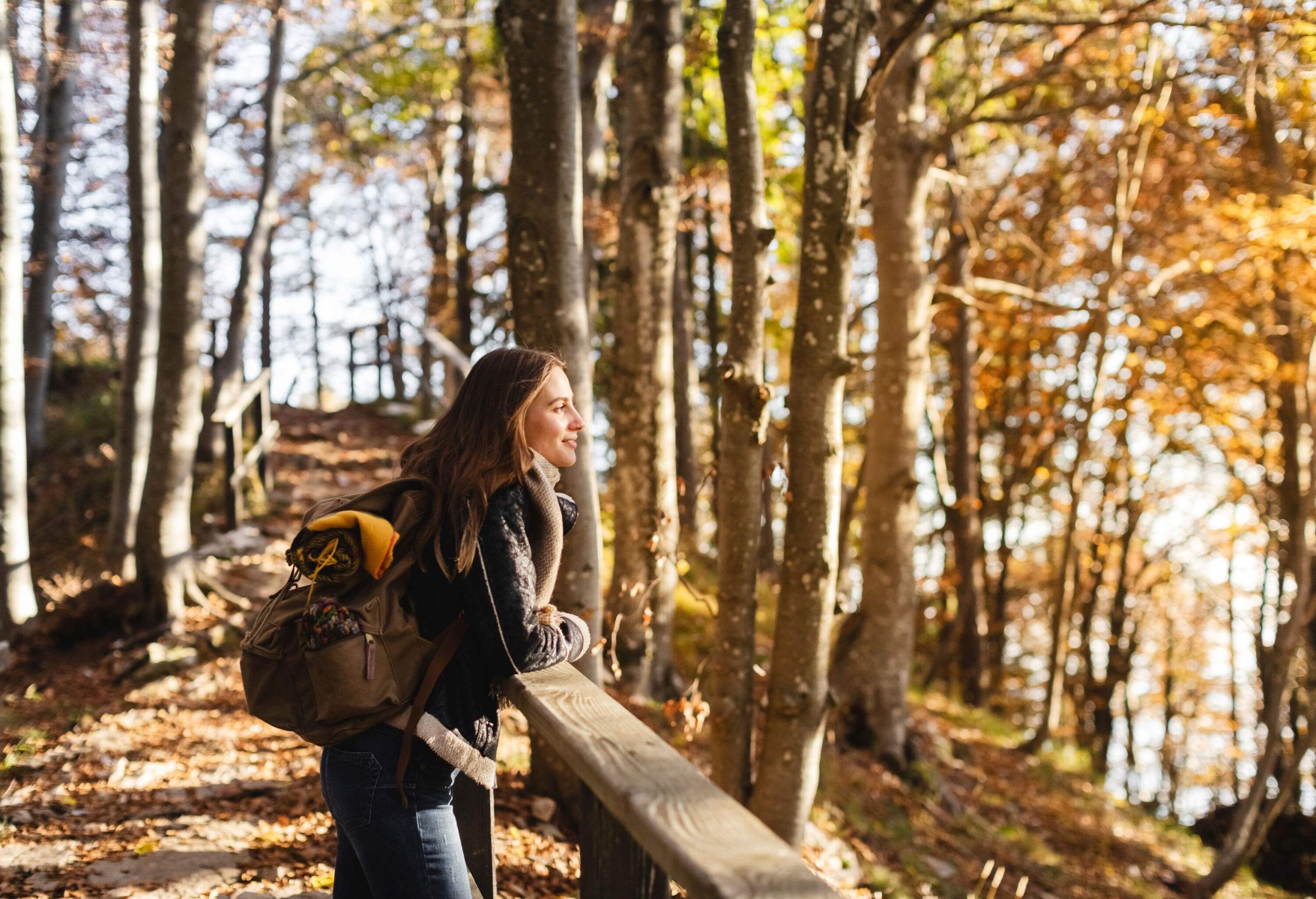 A female hiker leans on a wooden ledge and enjoys the nature views.