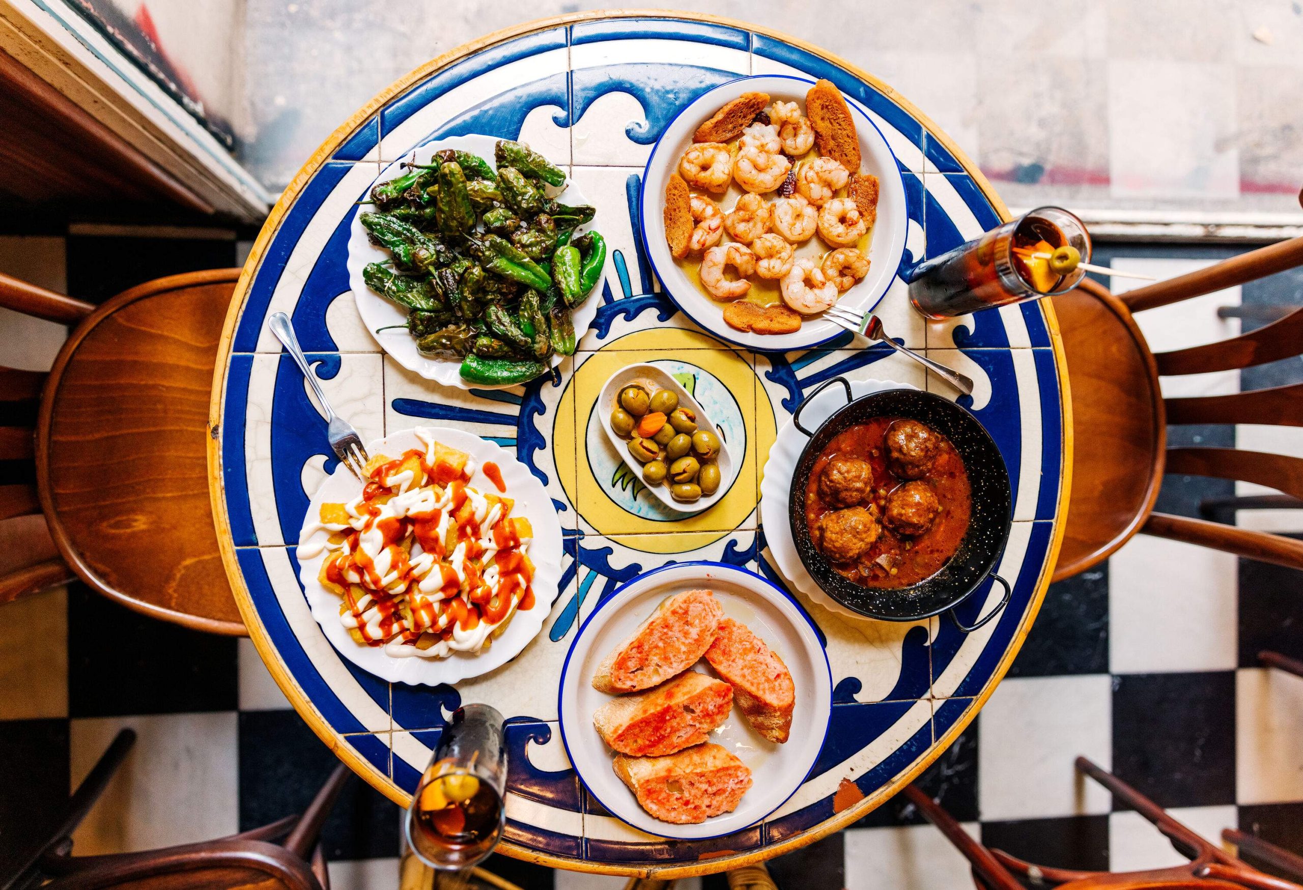 A gorgeously tiled table with a large array of Spanish food.