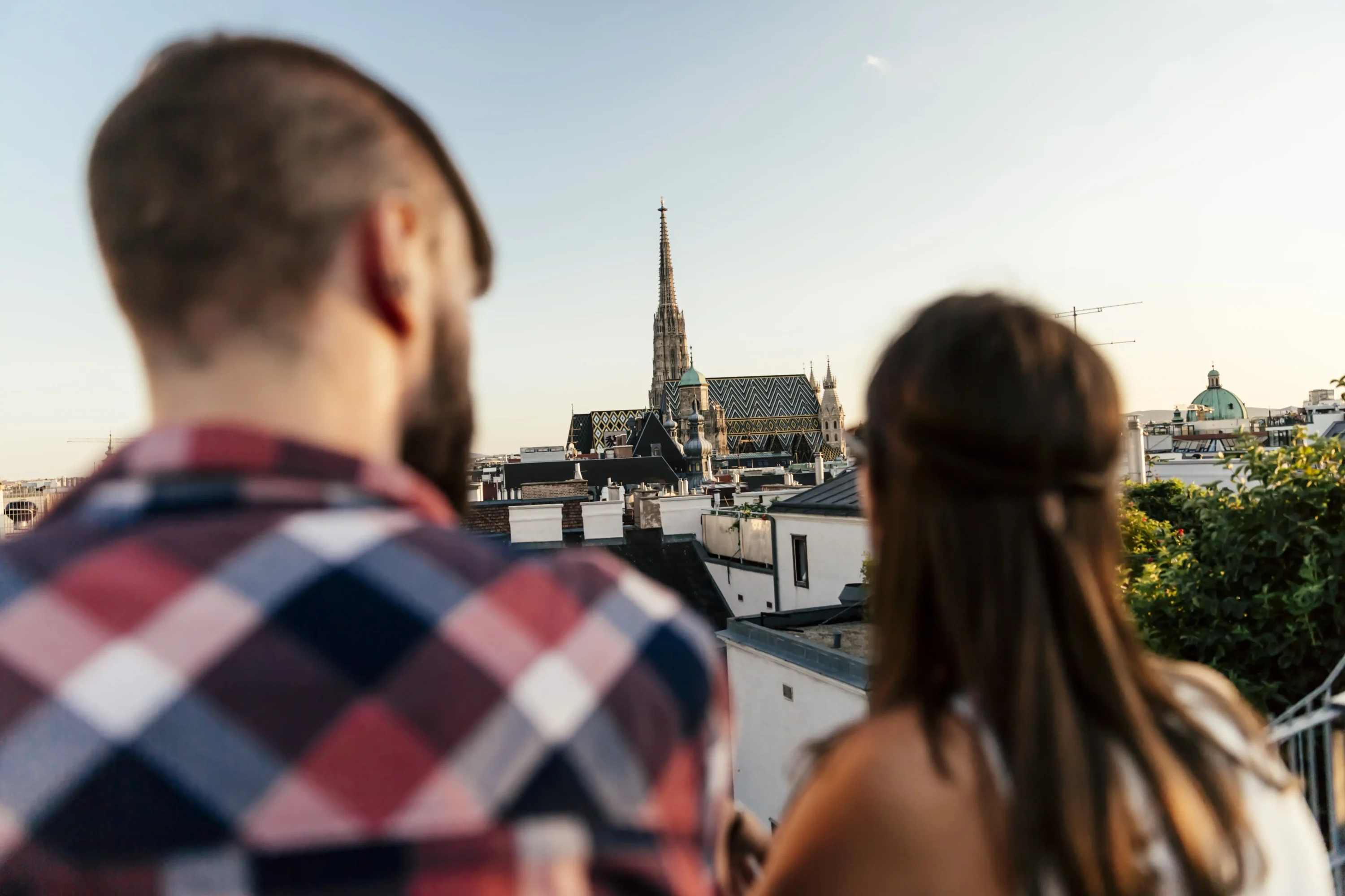 A man and woman on a terrace, looking over the city at a church spire.