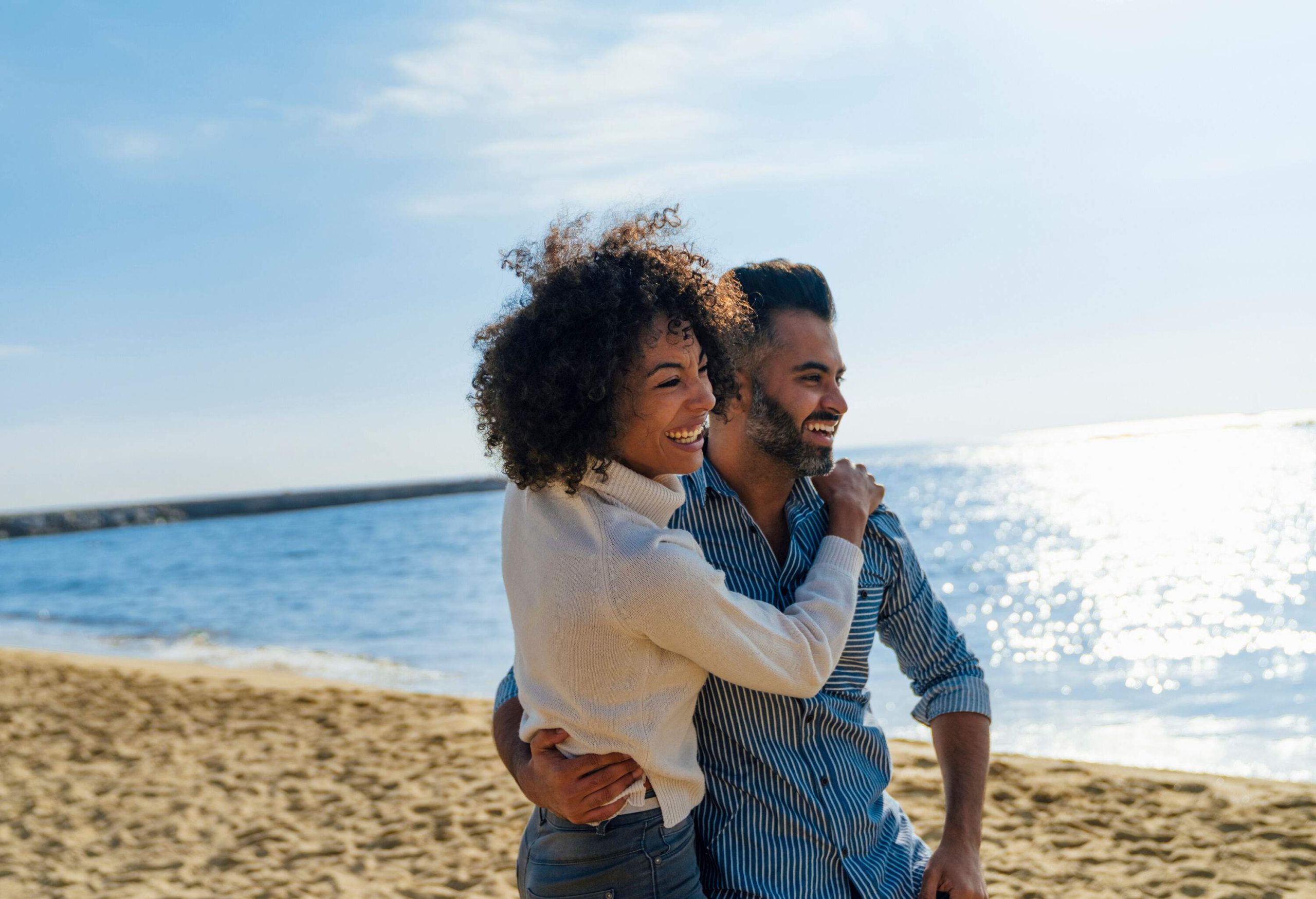 Happy couple embracing on the shore of a sparkling beach.