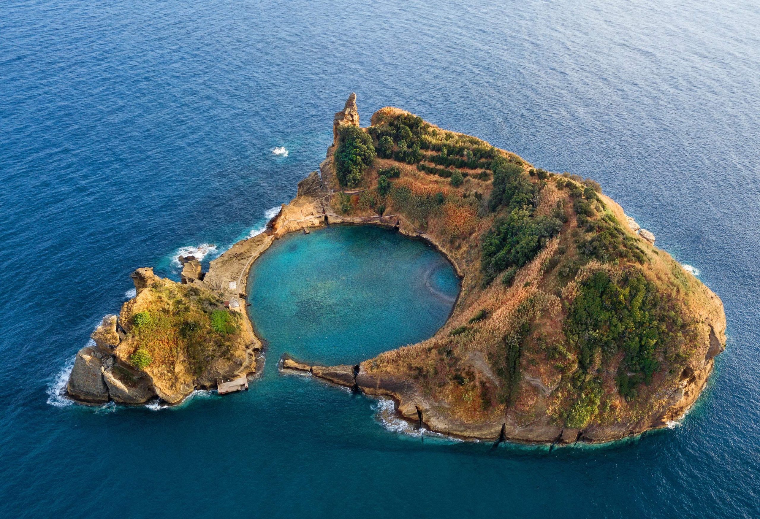 An islet with a sheltered bay surrounded by rugged slopes covered in vegetation.