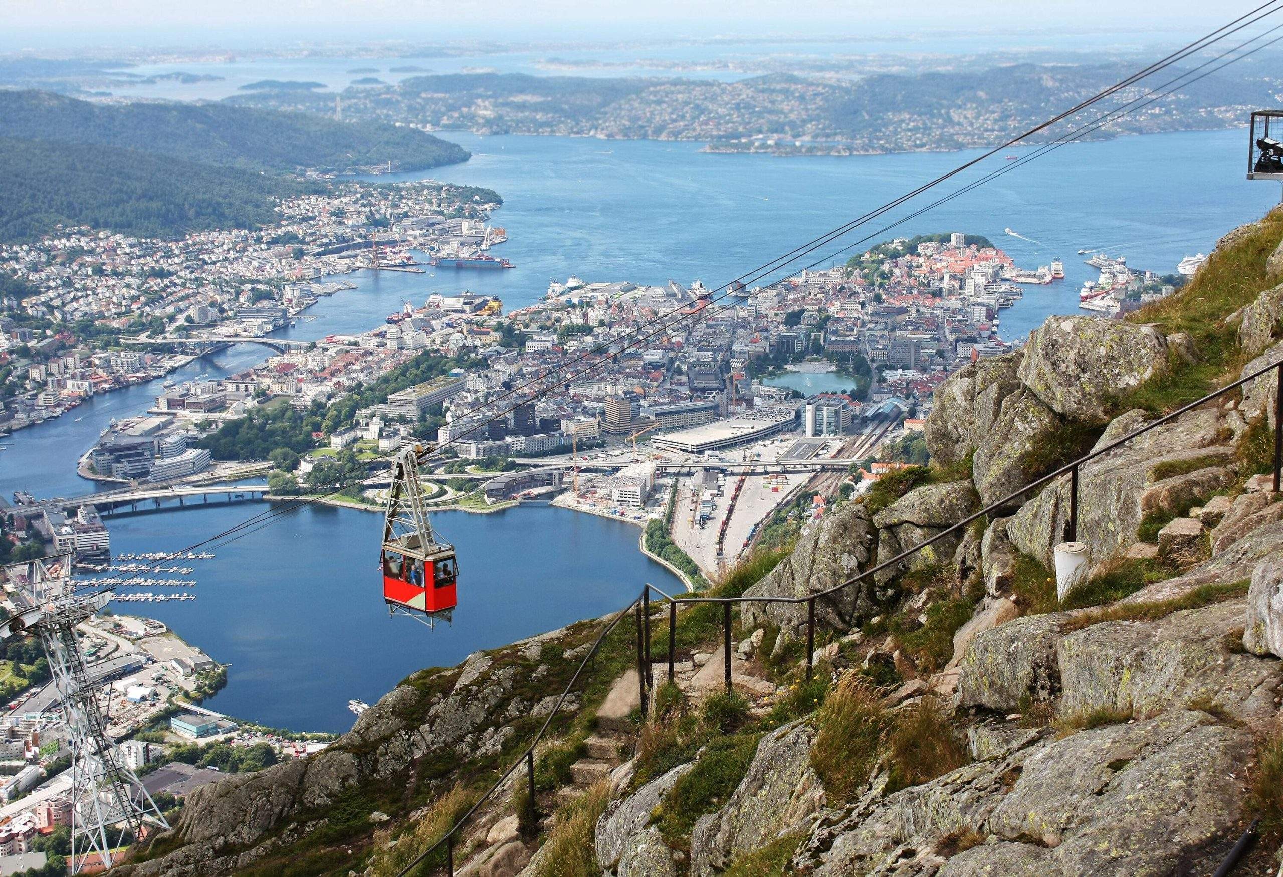 A red cable car traversing a ropeway with incredible views of the sea and the surrounding towns.