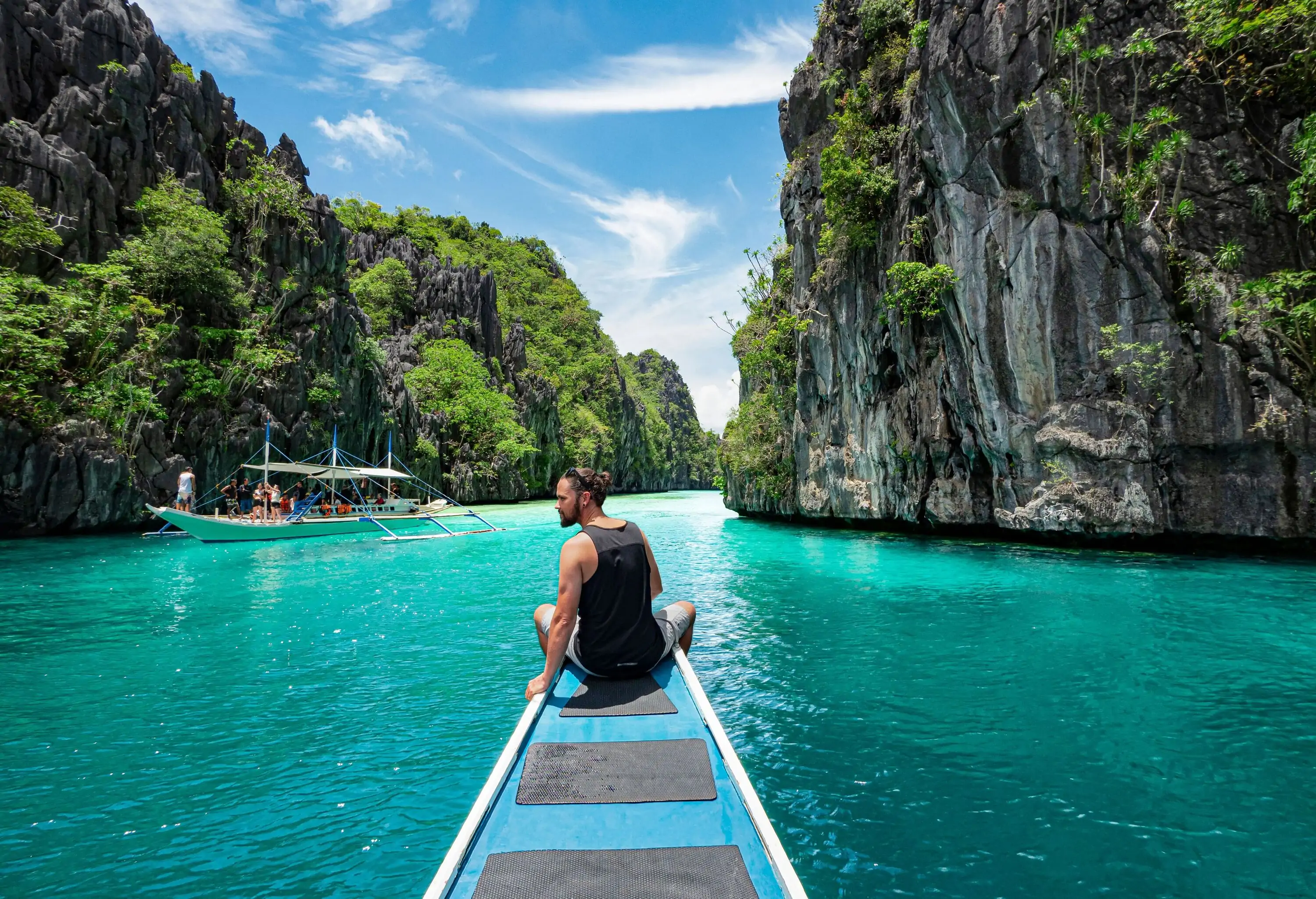 A curious traveller sits on the deck of a boat, surrounded by towering granite rocks that stand as majestic sentinels.