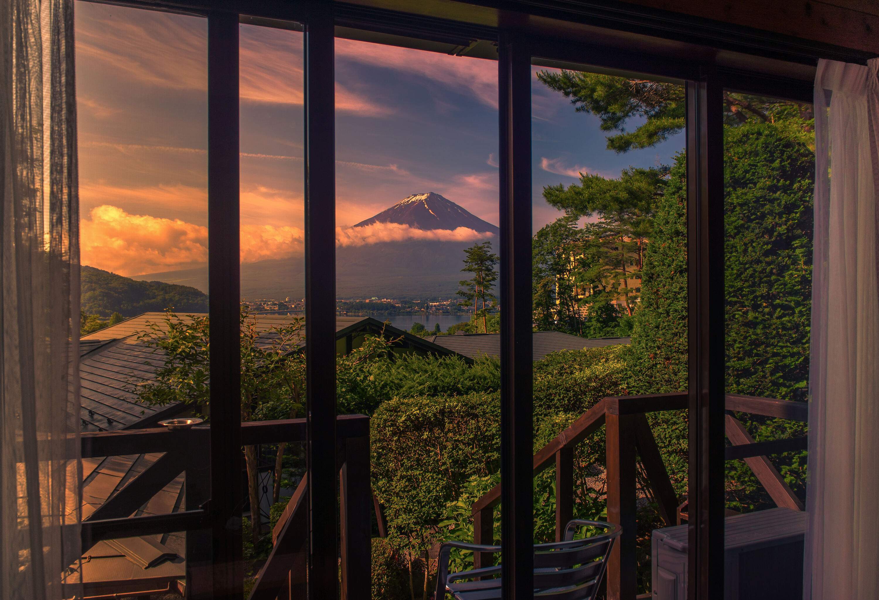 Peaceful scenery of Mount Fuji against the scenic twilight sky seen from a room's window.