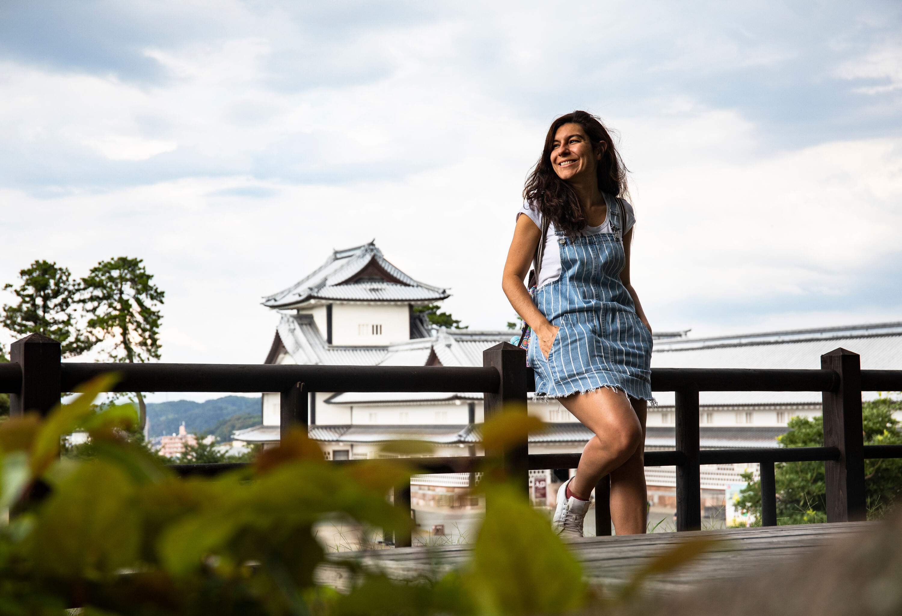 A woman in a striped jumper smiles as she sits on a wooden fence.