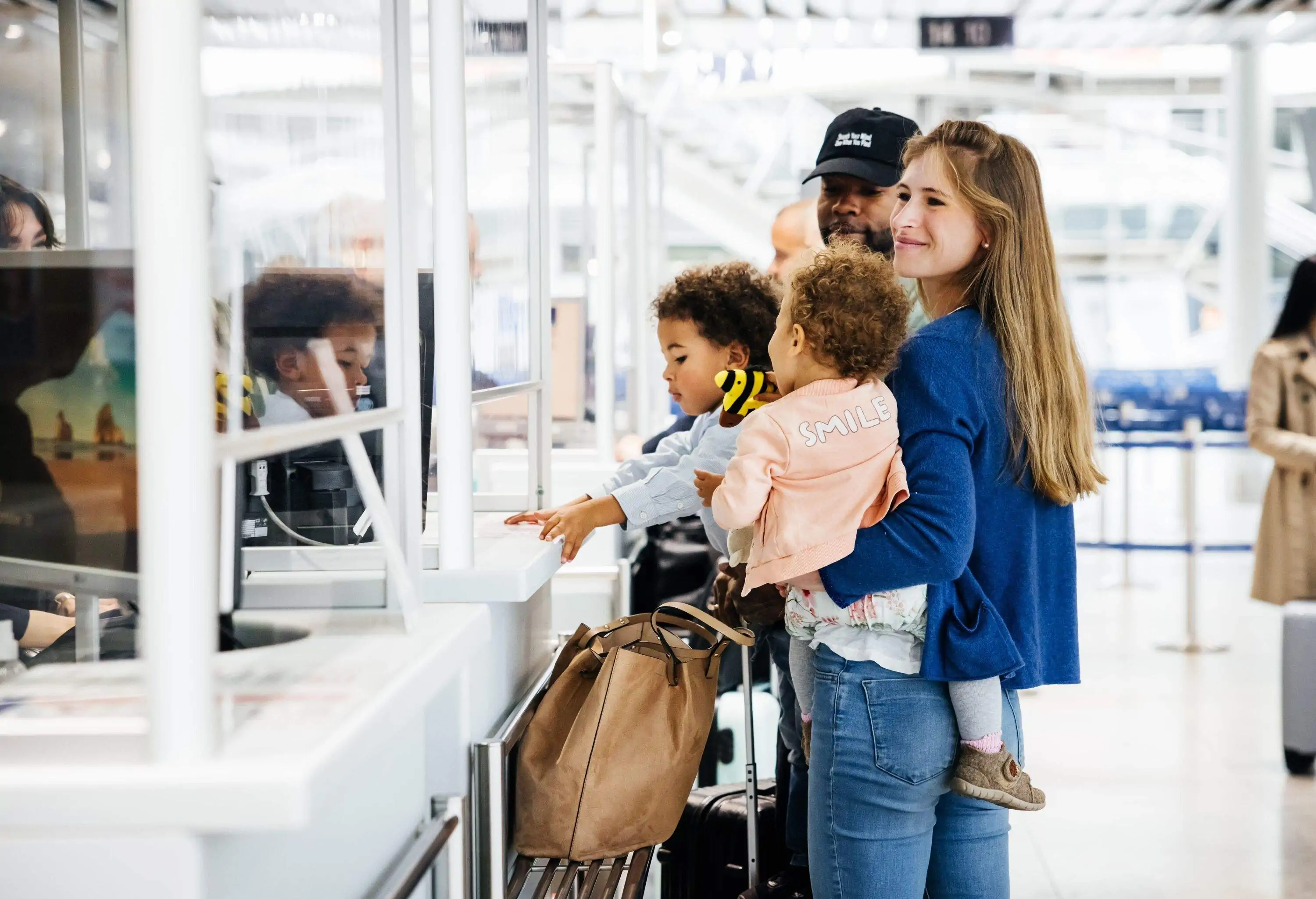 Family of four waiting at counter of a busy airport in the day