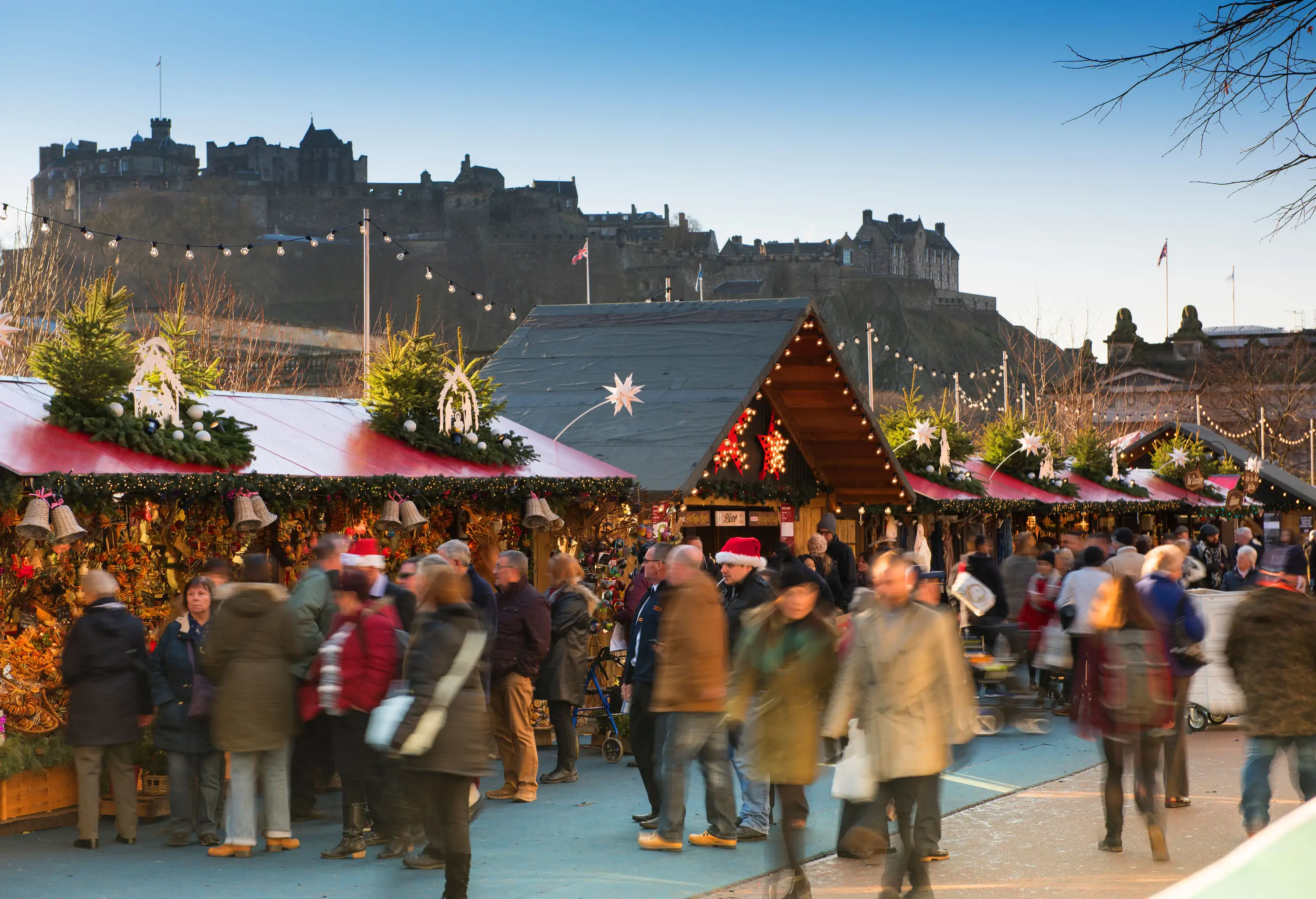 People strolling on a crowded street along a row of decorated shops selling a variety of souvenirs.