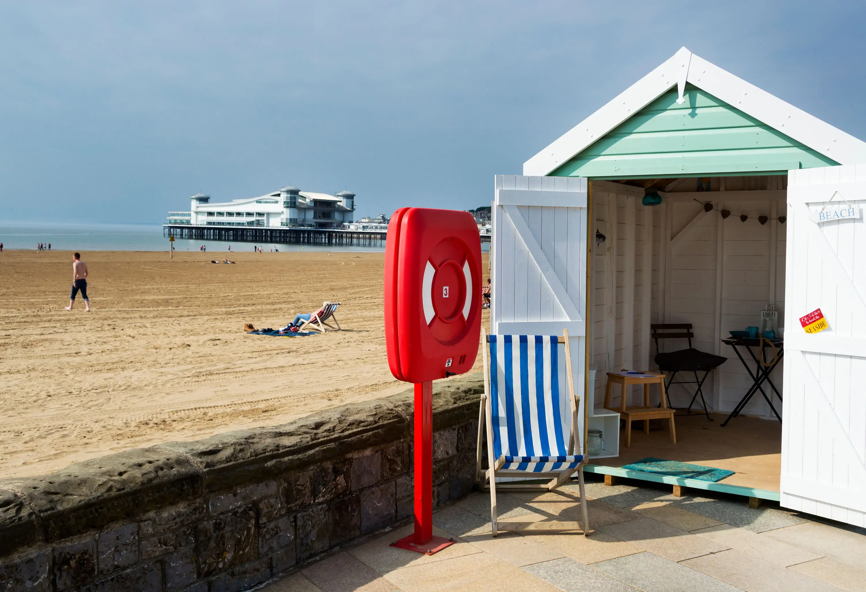 People on the sandy shore, basking under the warm sun and enjoying the view of the seaside pier.