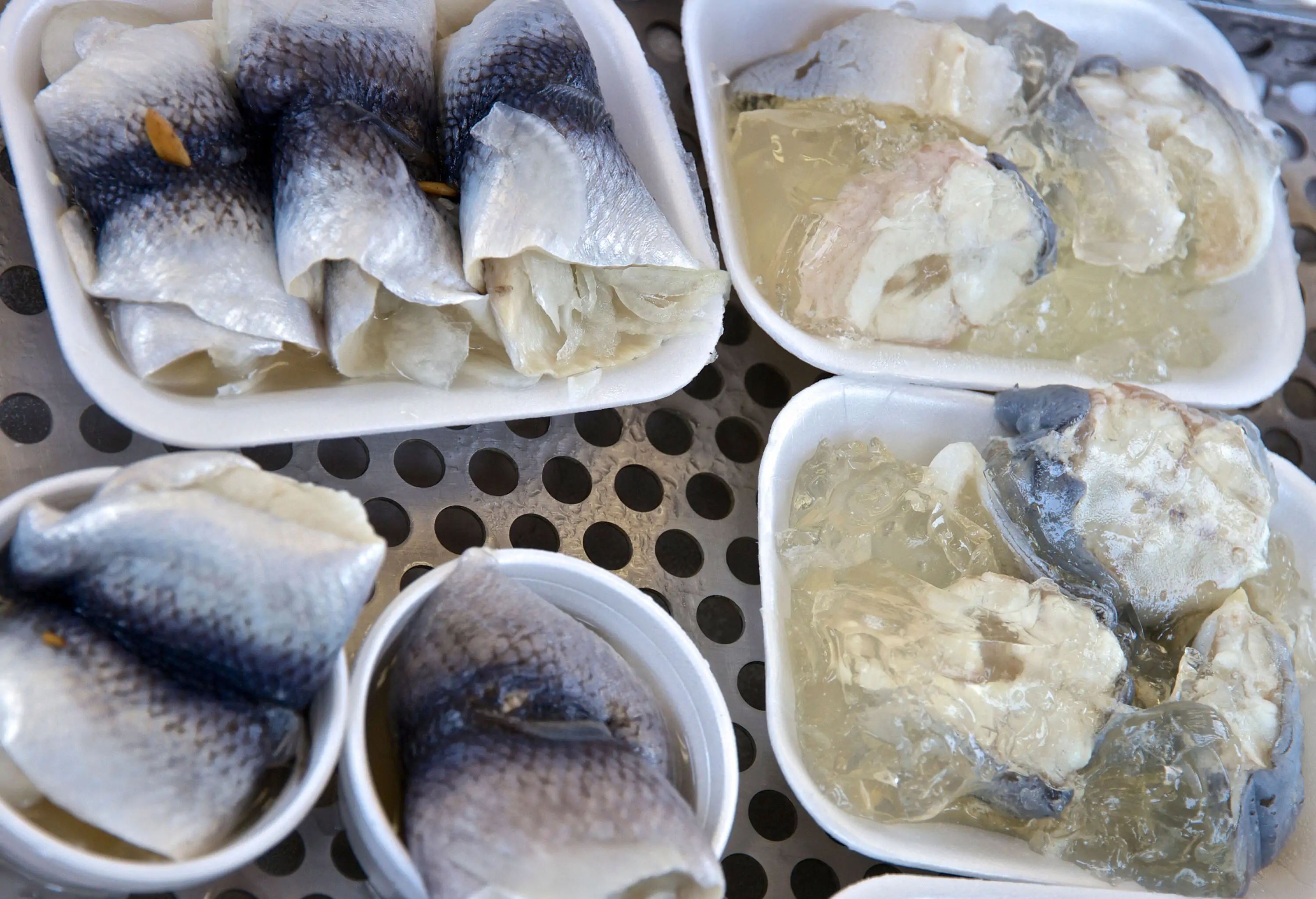 Fresh fish meat slices served on disposable cups and plates.
