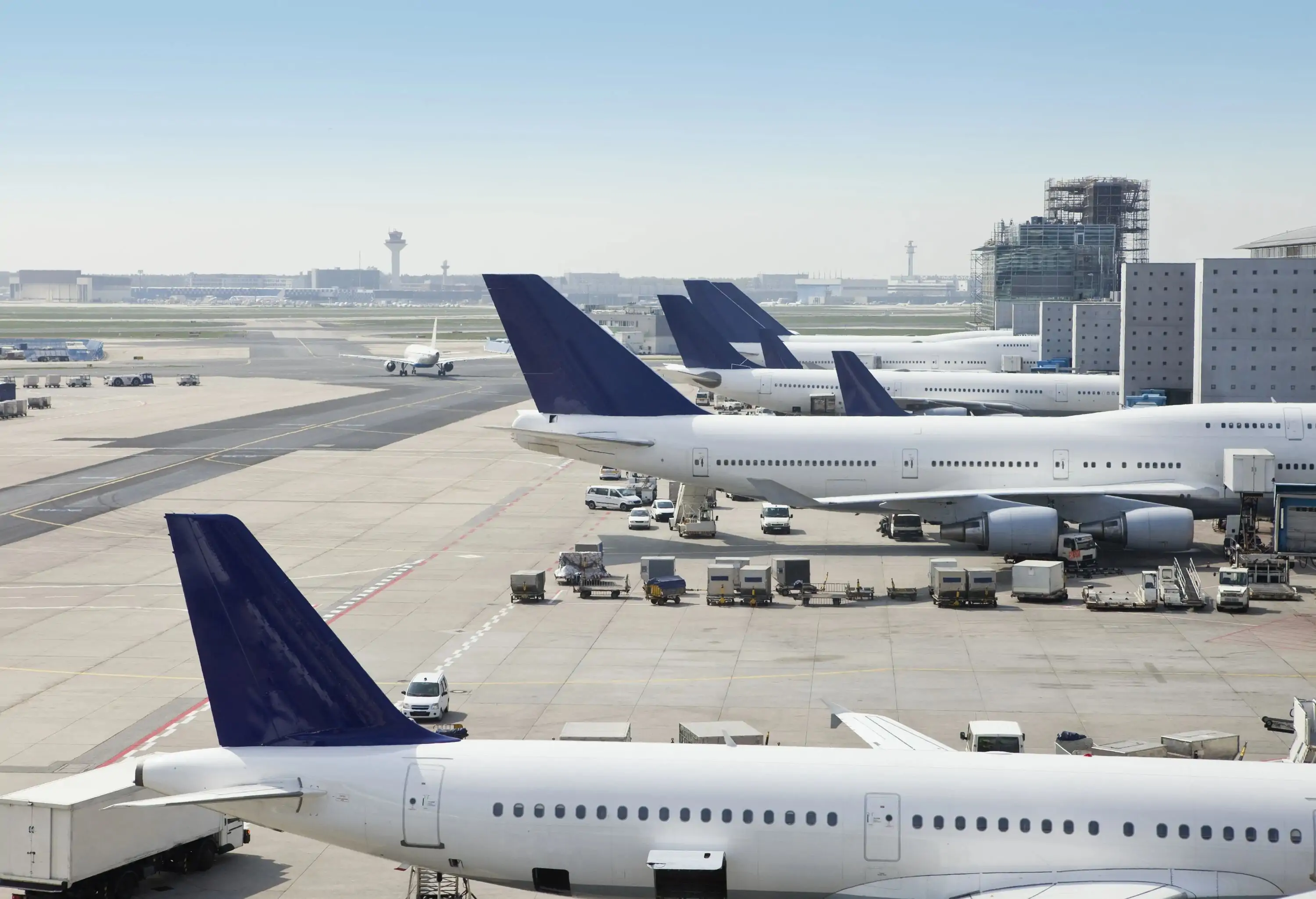 Side profile view of an airplane on the tarmac at an airport, with cargo being loaded into the aircraft's hold.