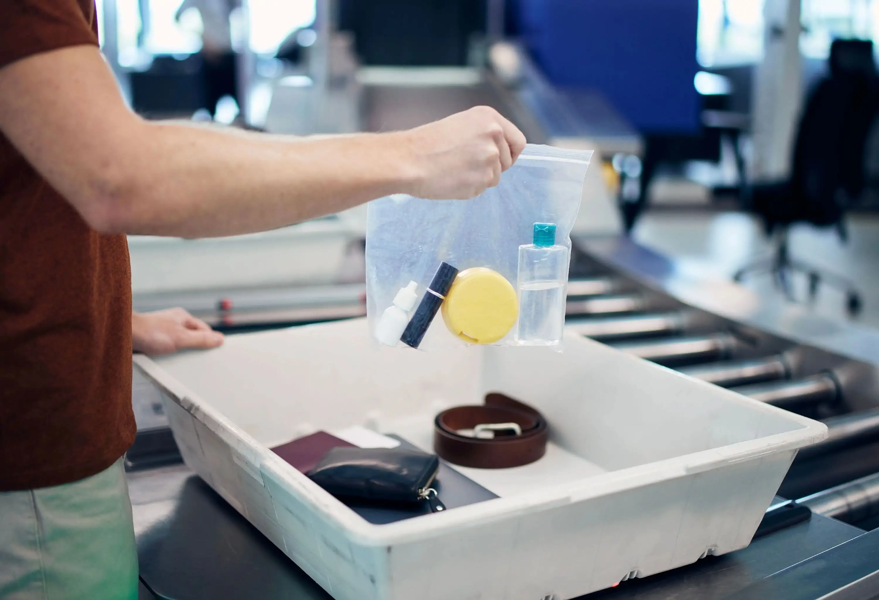 A man packing a plastic bag with liquids at the airport security check