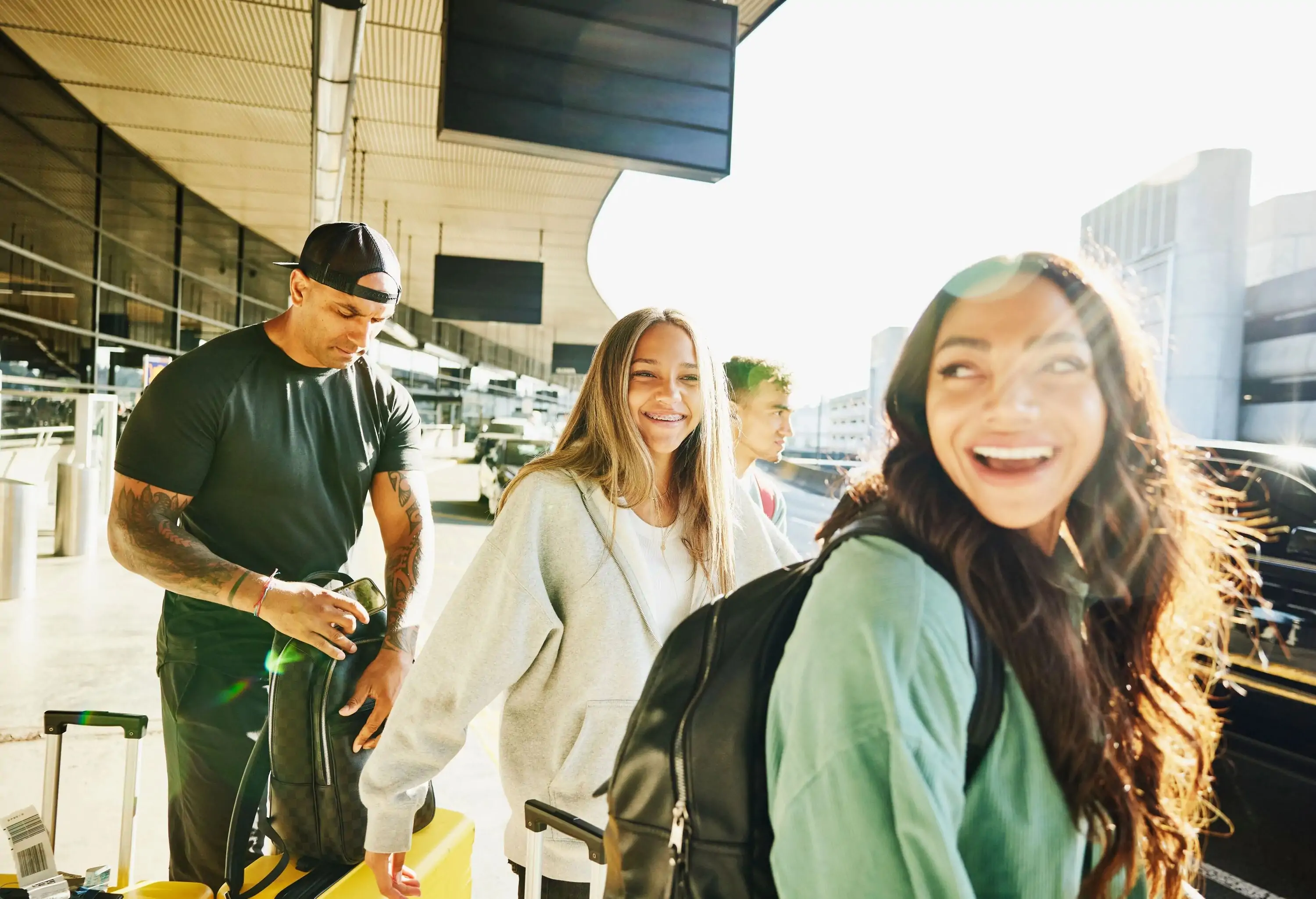 Medium shot of smiling family arriving curbside at airport before departing on vacation