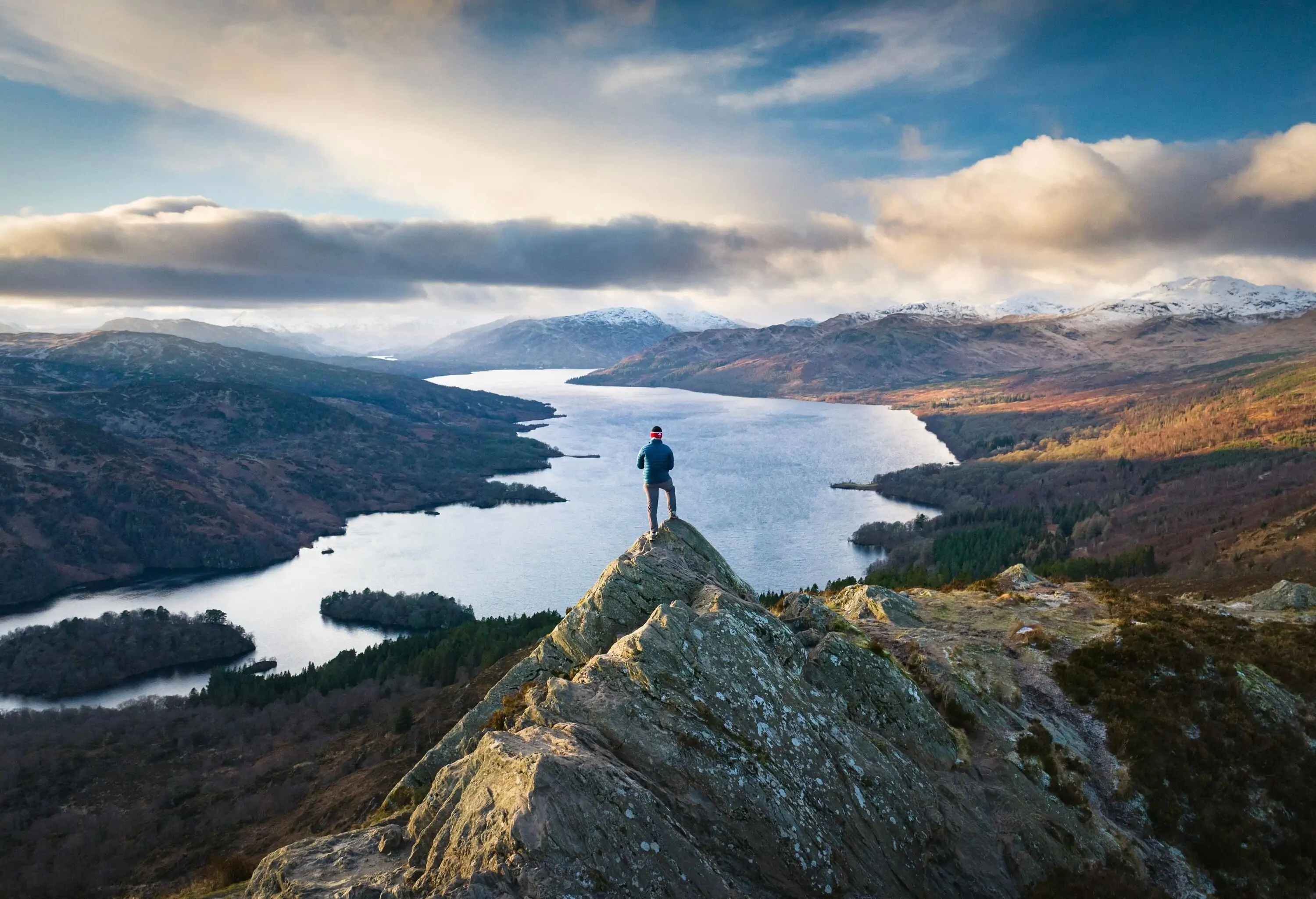 Hiker on the summit of Ben A'an, Scottish Highlands at sunset