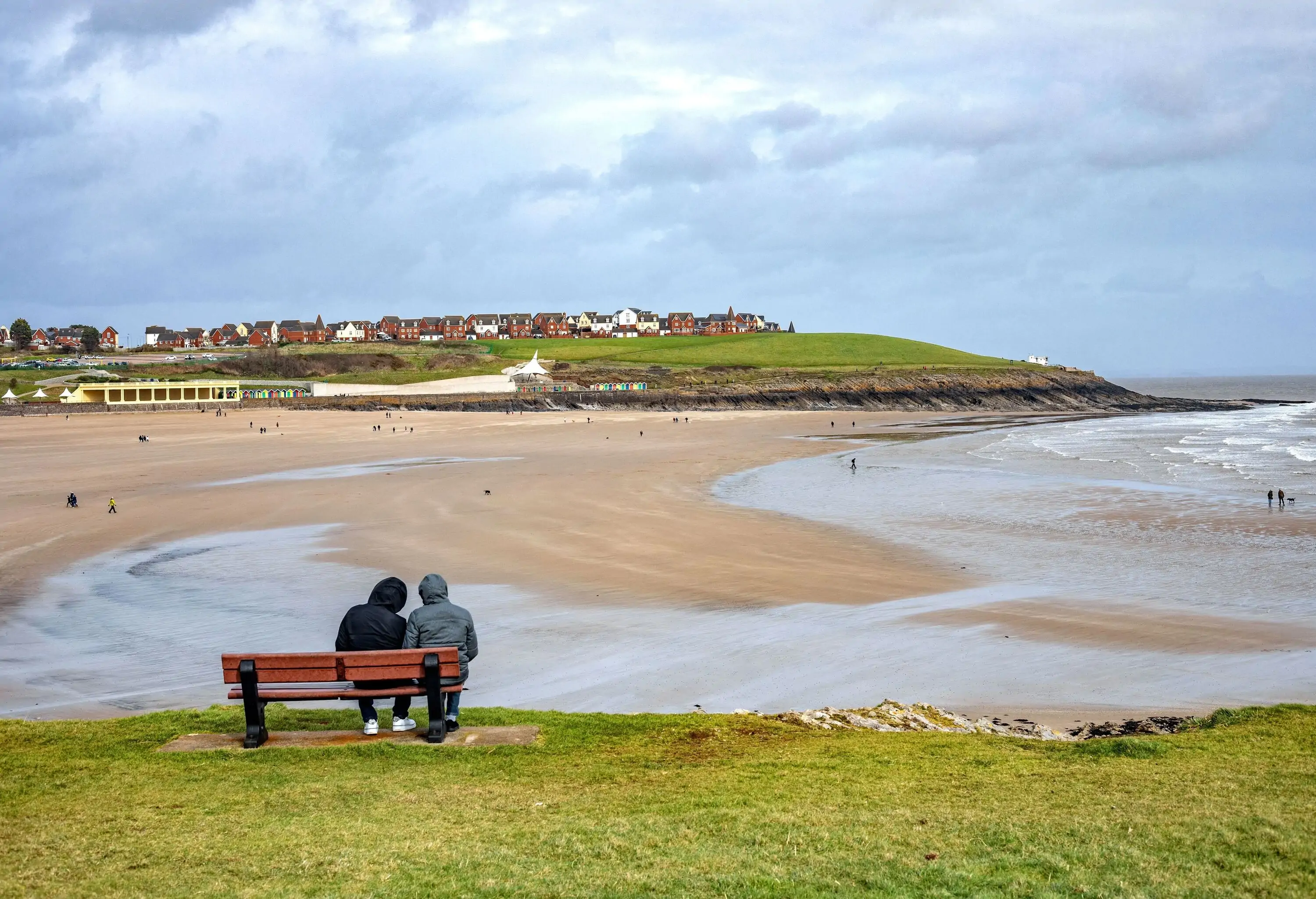 Couple Sitting on Bench and Looking at View on Whitmore Bay in Wales.