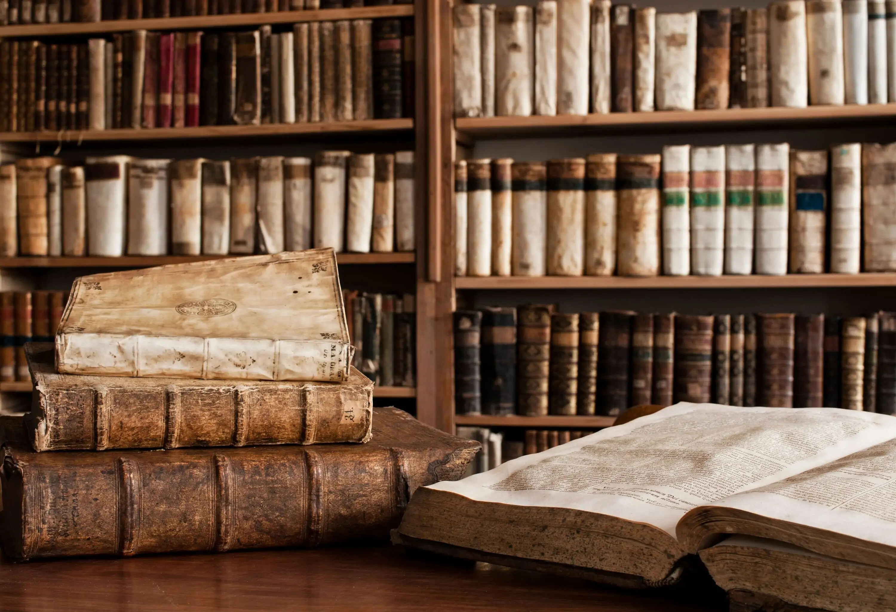 Antique books on the wooden table and displayed on the shelves in the library.