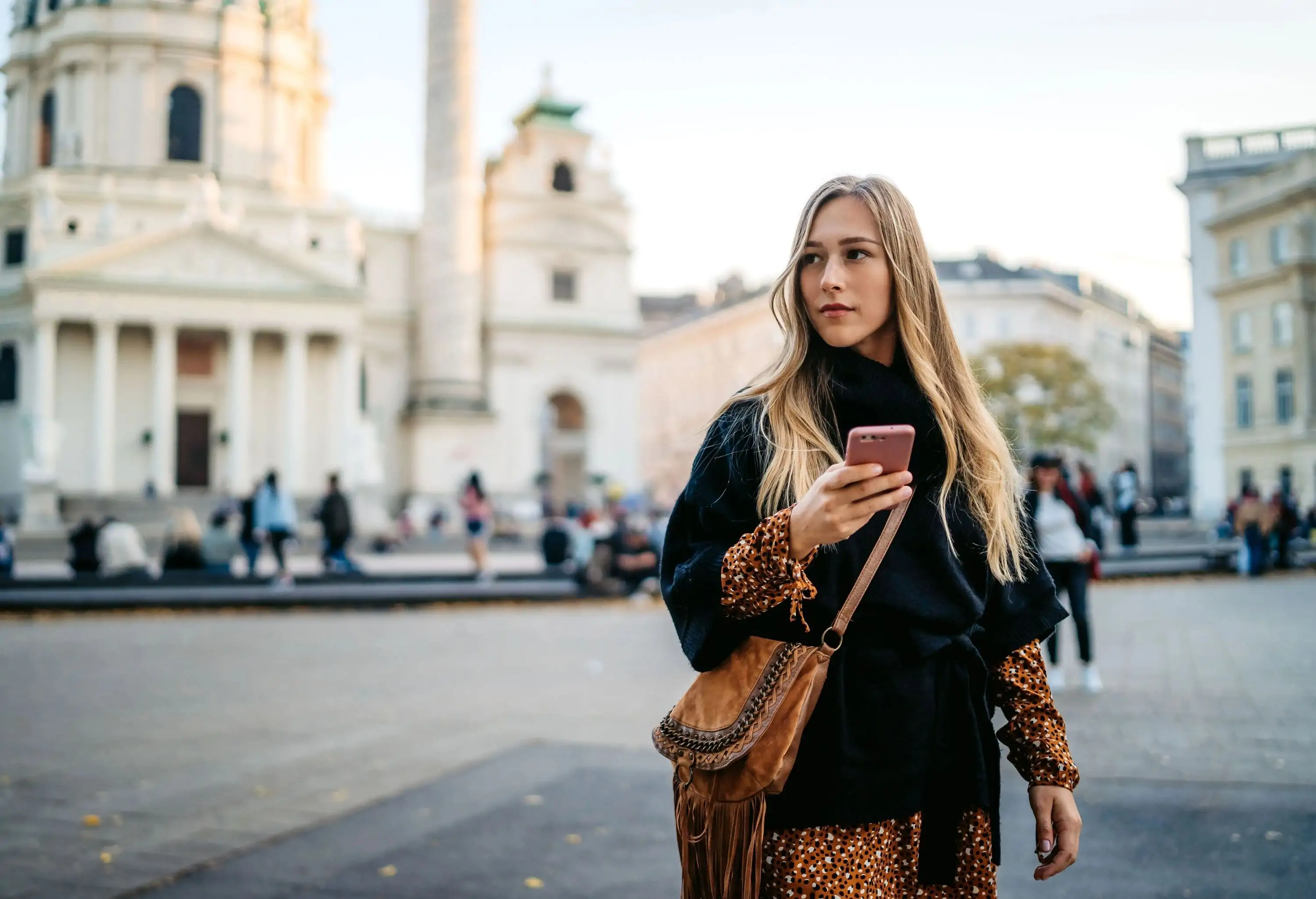 A woman wandering around a town square with her phone in her hand.