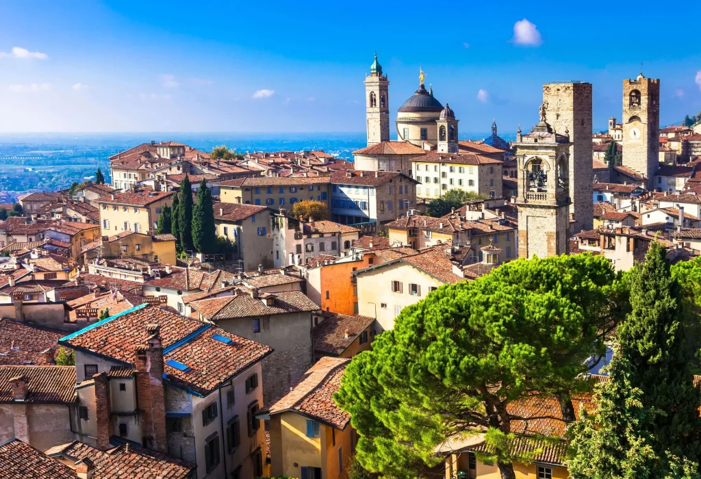 A skyline of an old town dominated by classic brick-roofed buildings, a Romanesque domed church and soaring bell towers.