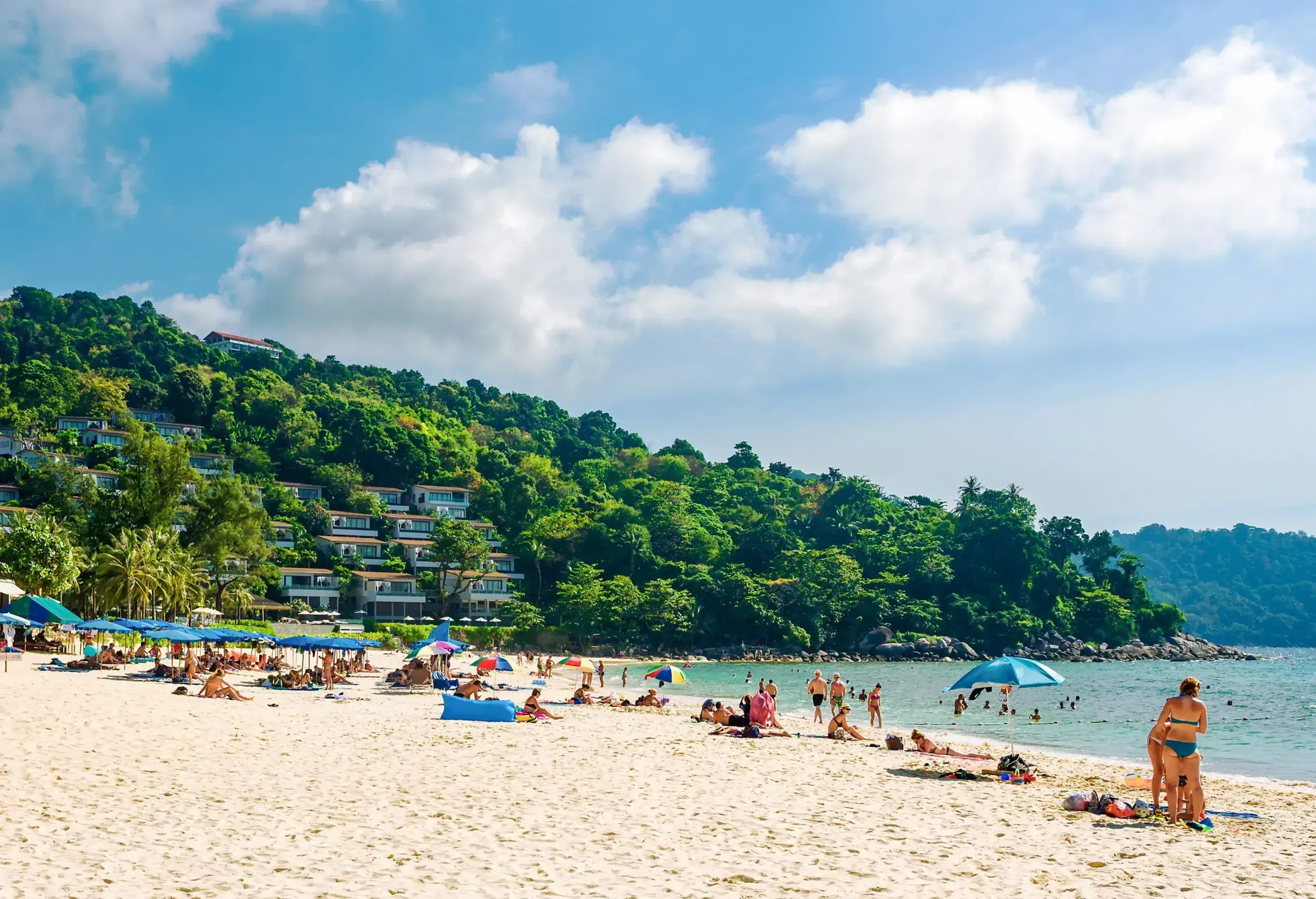 Many tourists visited the beach next to identical cottages clustered on the lush mountainside.