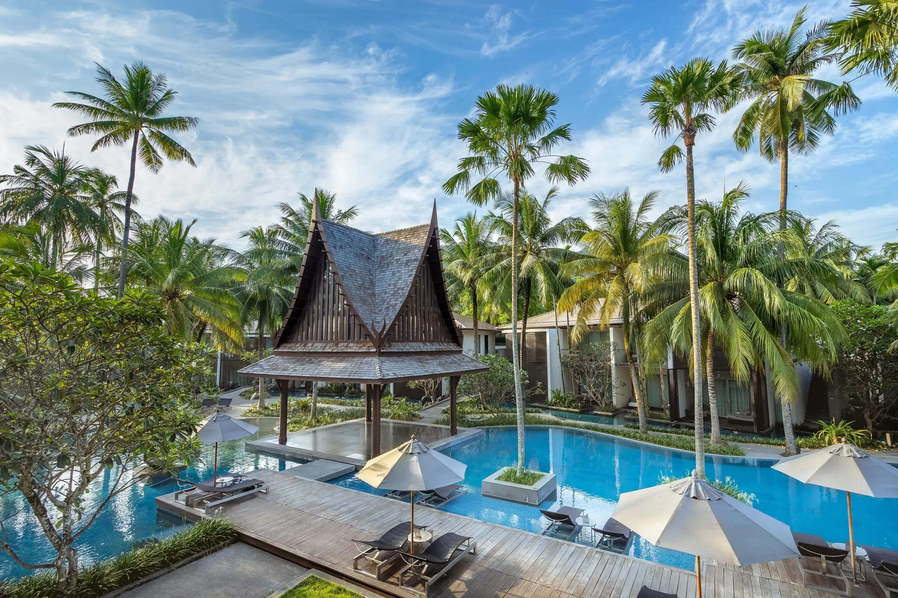 A large swimming pool with tall palm trees and a pagoda-style structure in the middle