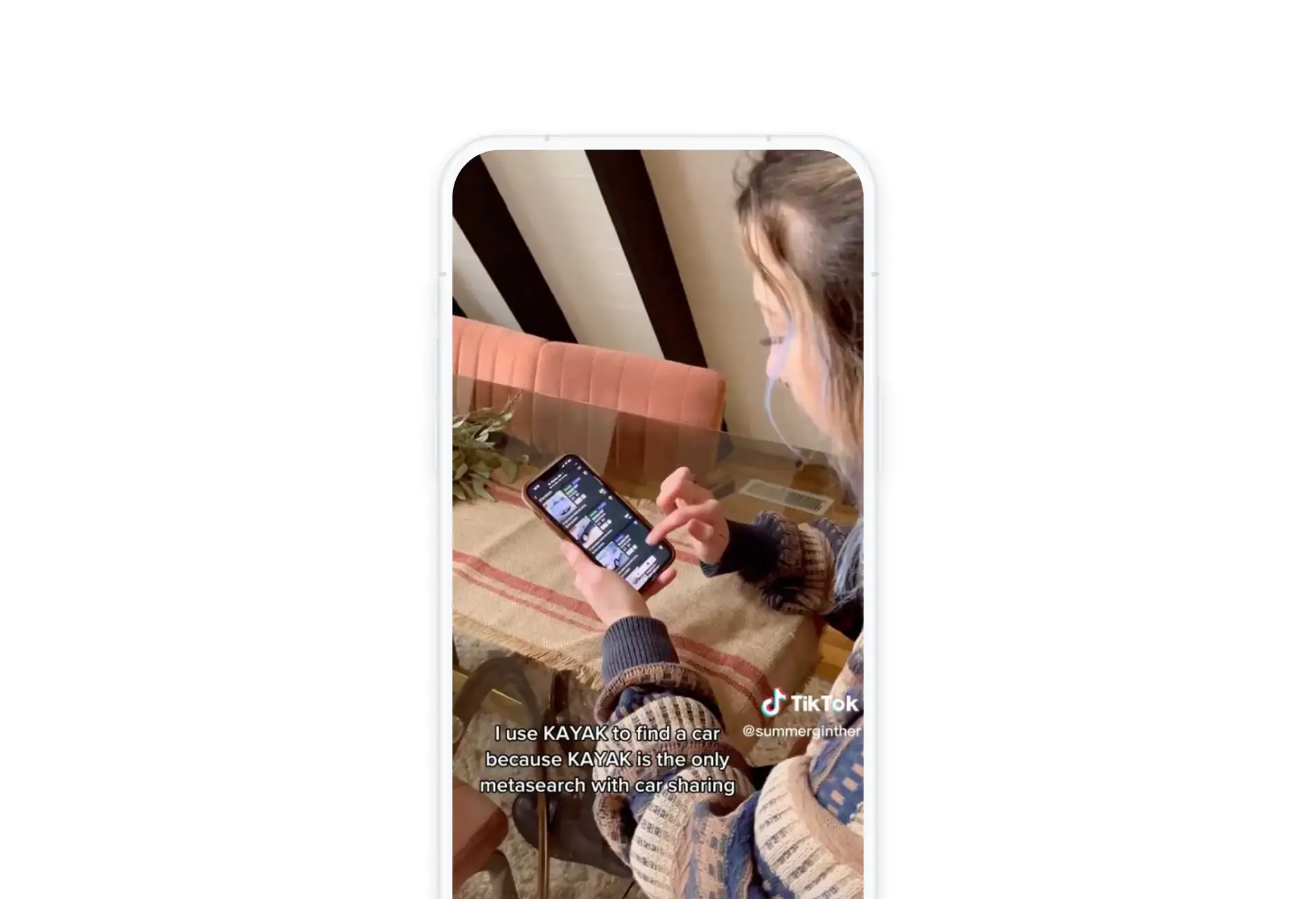 Young woman browsing travel content on her phone in a cozy setting.