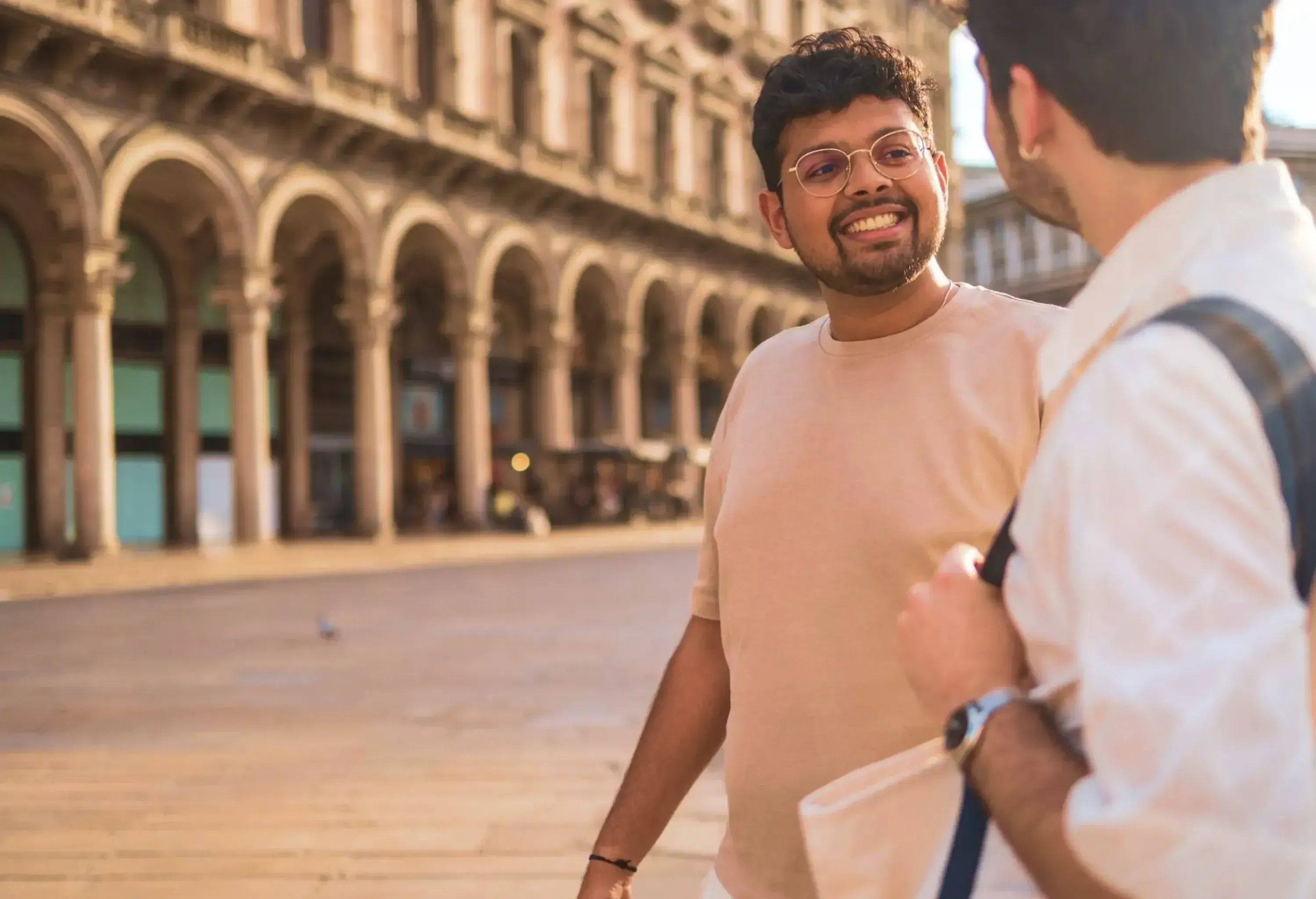 Two young male tourists are walking and talking in galleria vittorio emanuele ii in milan, italy, enjoying their vacation