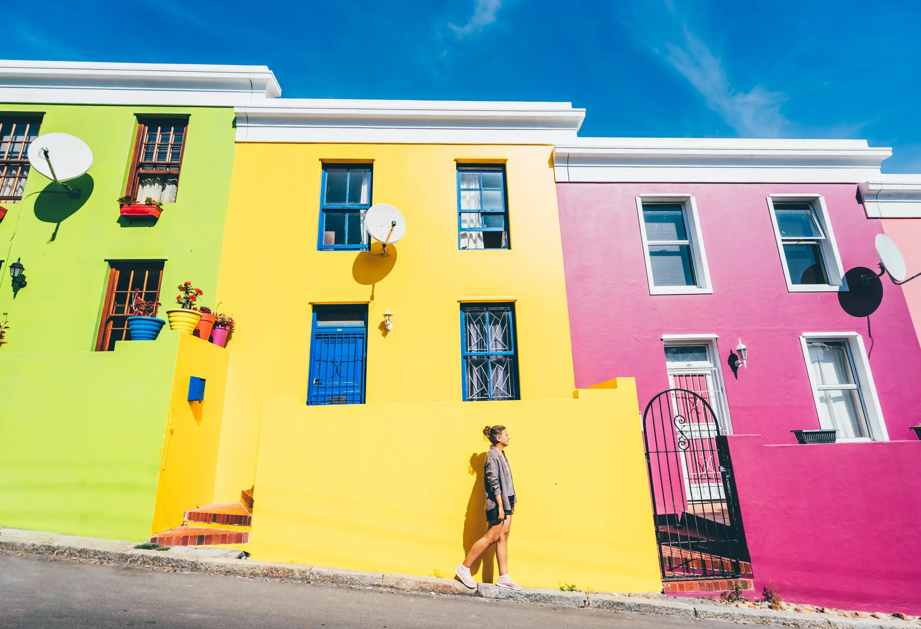 A woman walks in front of colorful houses in Bo-Kaap, Cape Town, South Africa.