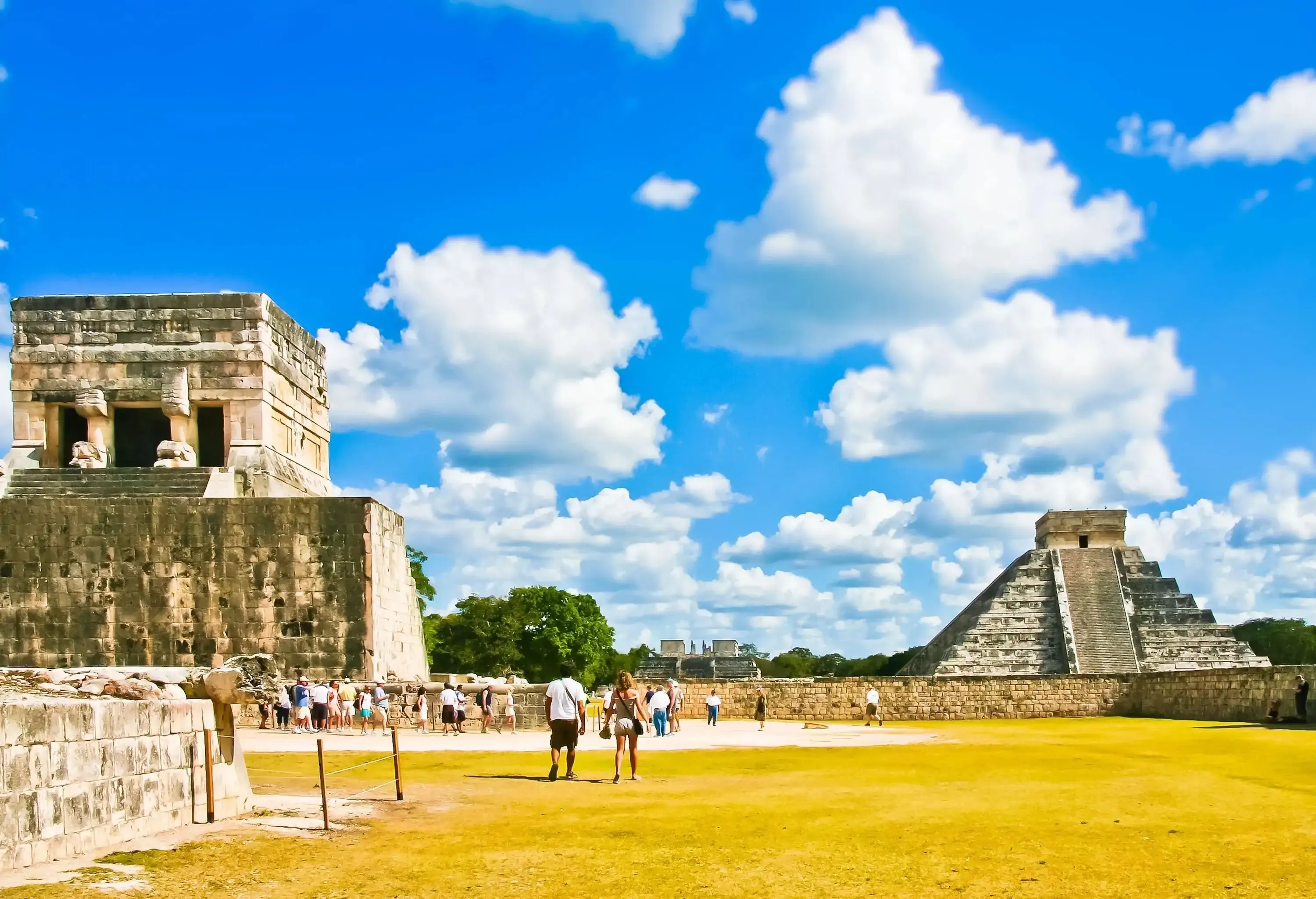 Tourists wander on an archeological site showcasing the ruins of ancient buildings and pyramid temples.