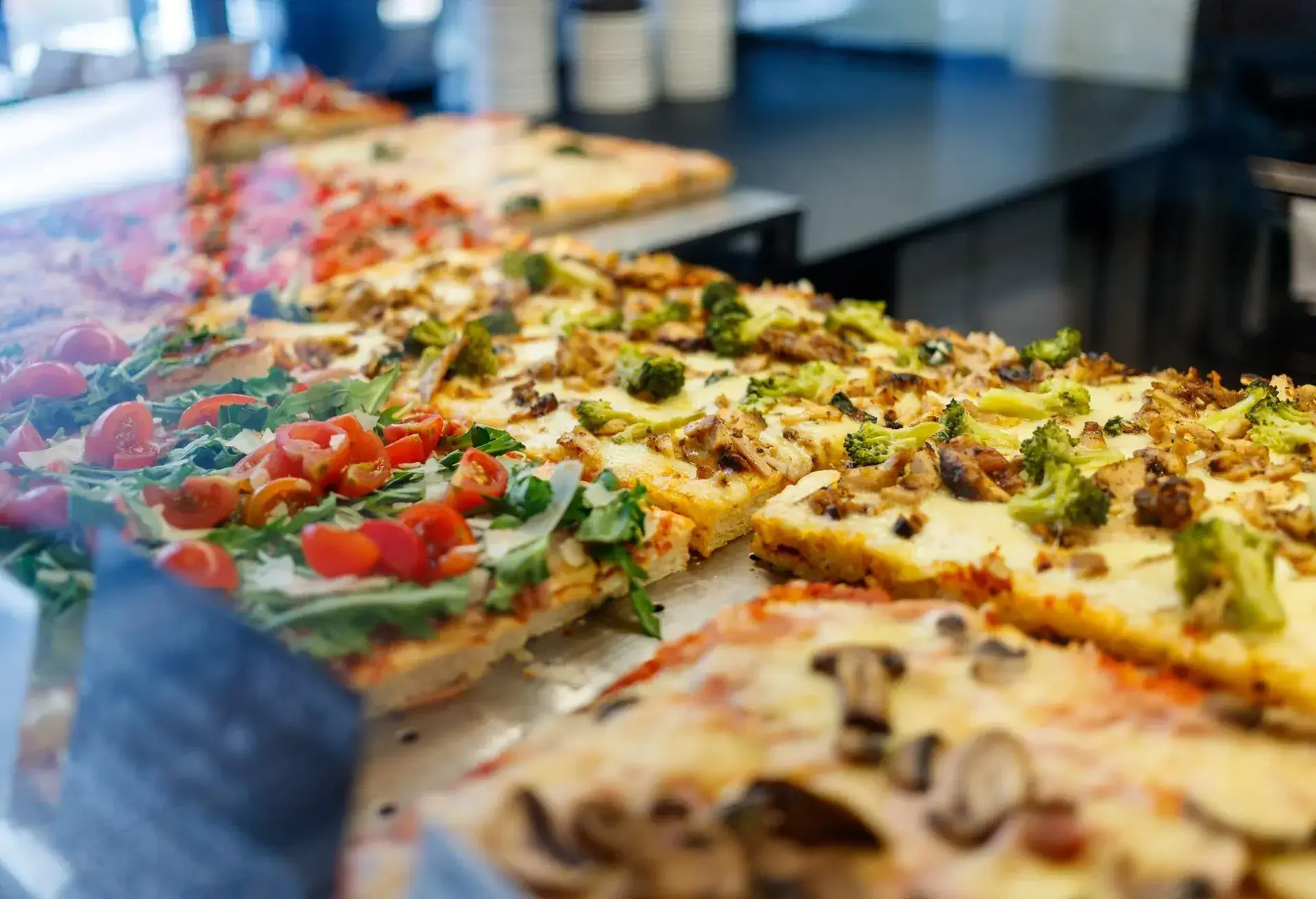 Various types of pizza al taglio in pizza place glass showcase