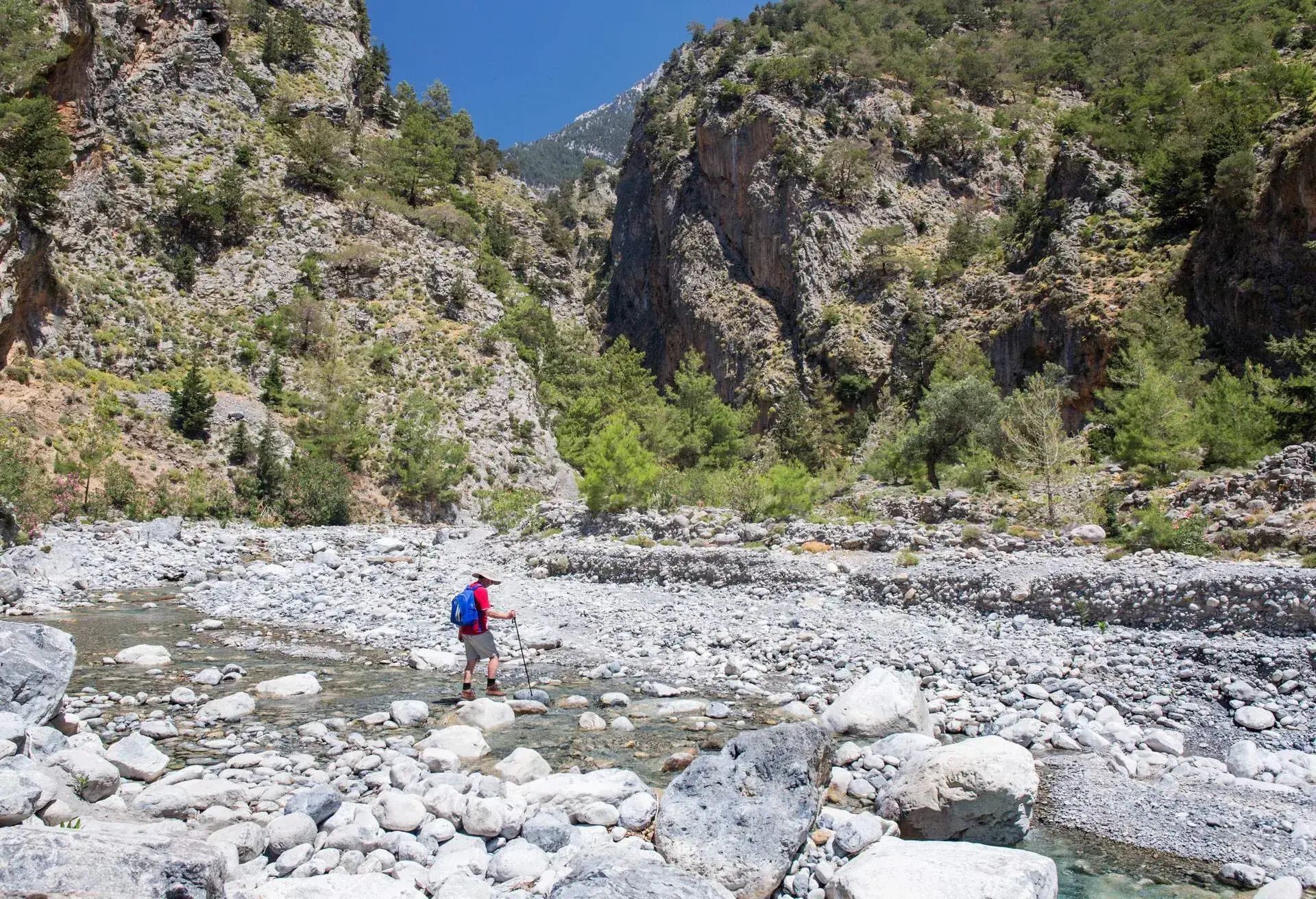 Hiker crossing stream at entrance to the Samaria Gorge, Samaria National Park, near Agia Roumeli, Hania (aka Chania), Crete, Greece, Europe