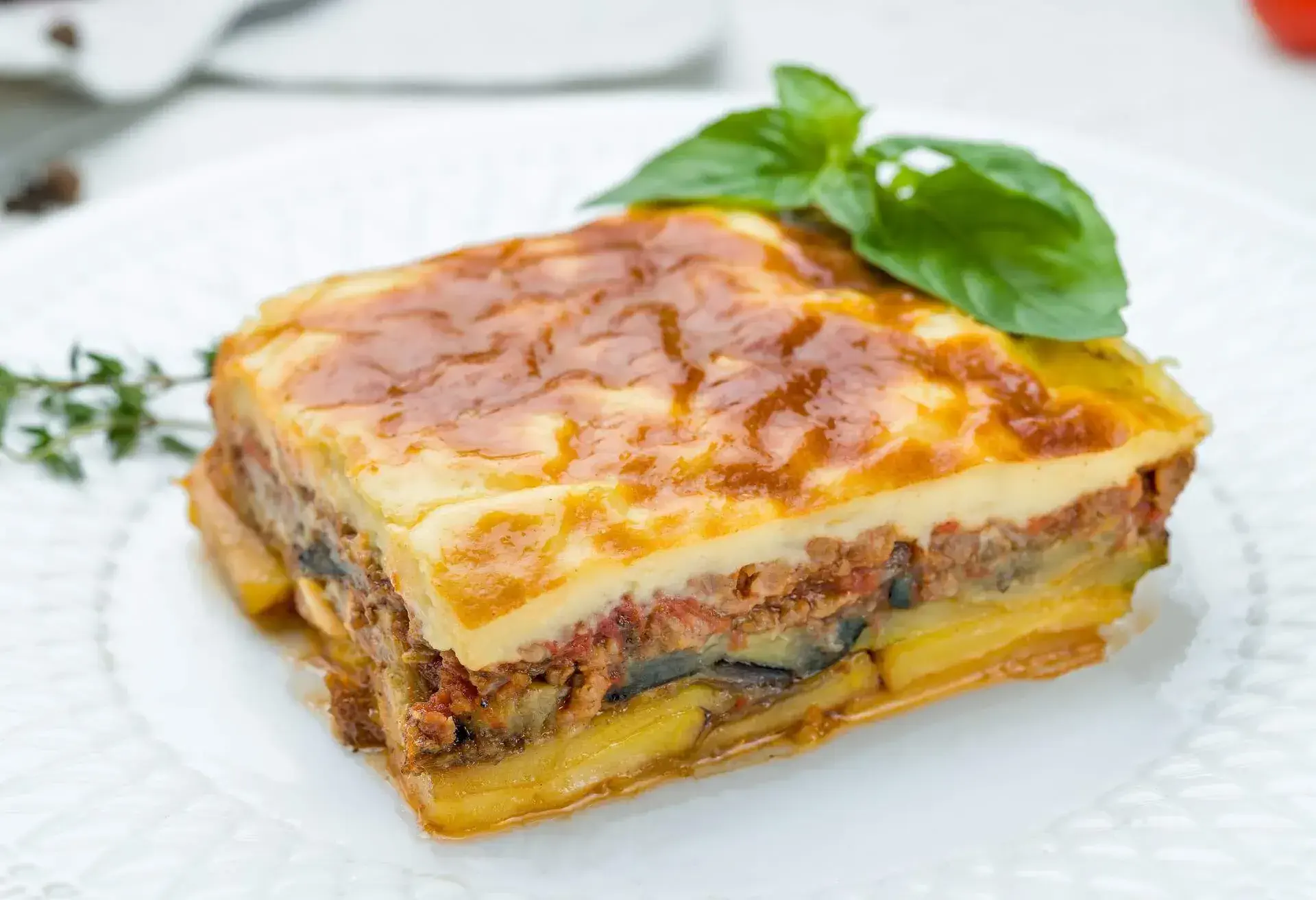 Eggplant moussaka Greek cuisine on white plate on white concrete table